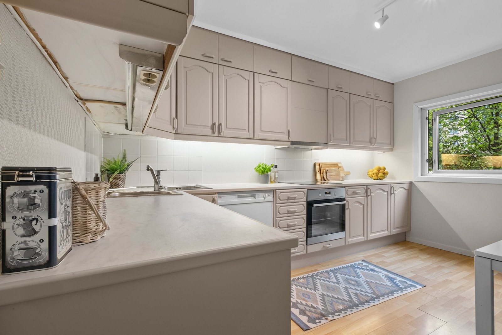 Kjøkkenet er pent og praktisk, med beige profilerte fronter og fliser over benkeplaten. Galleribilde