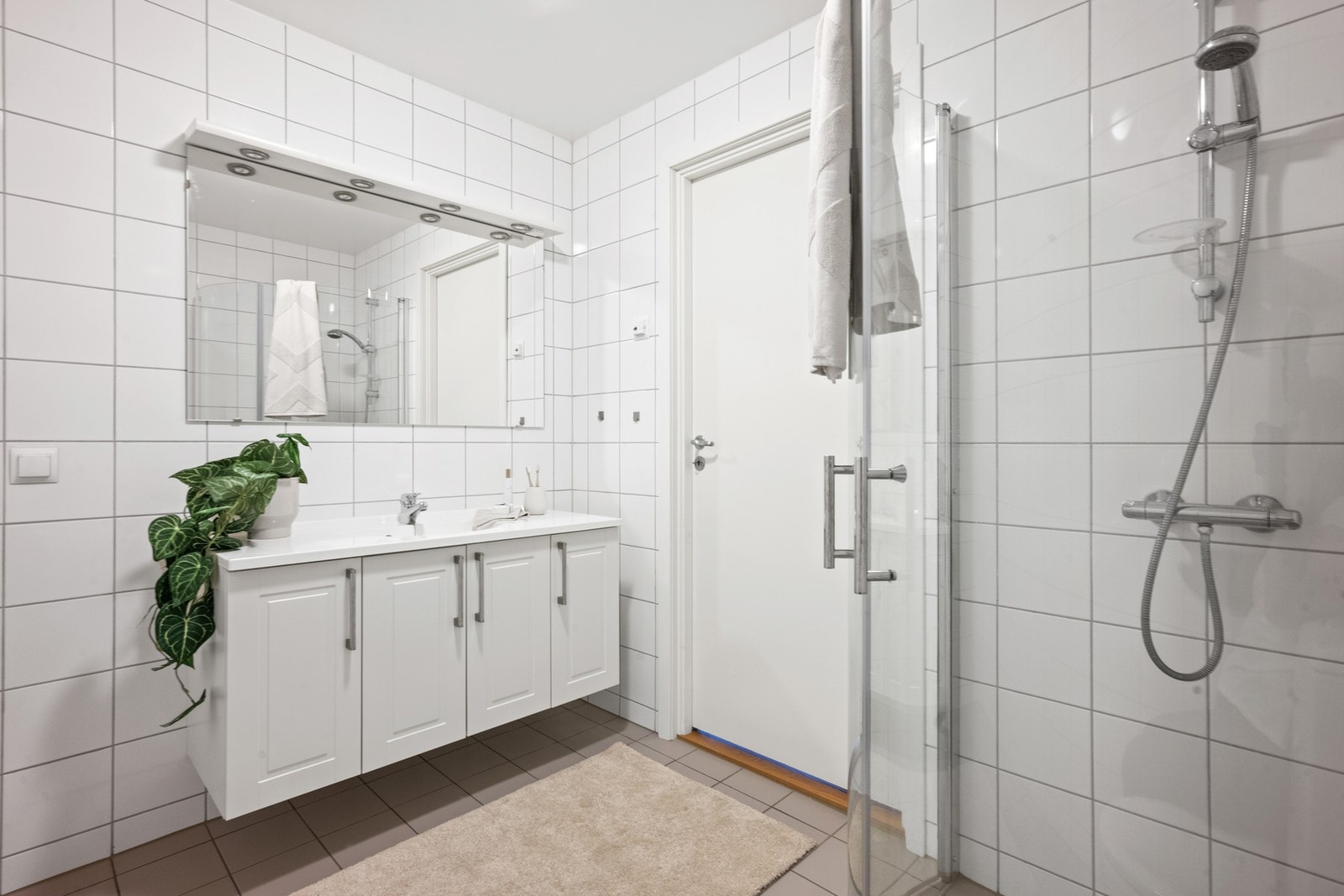 Badet har keramiske fliser på gulv og vegger, varmekabler og en praktisk utforming. Galleribilde