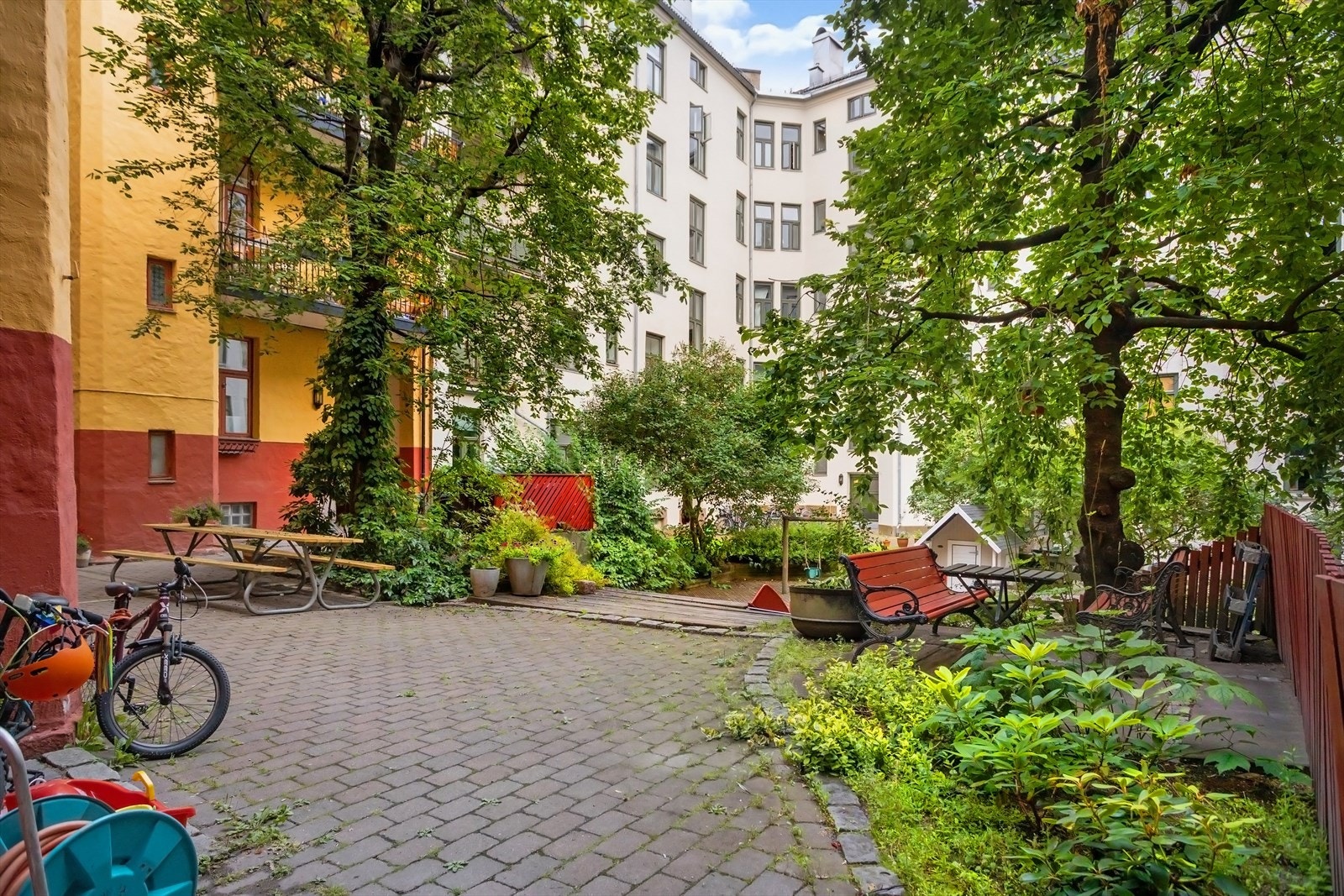 Idyllisk bakgård med sittegrupper, sykkelparkering og lekeapparater. Galleribilde