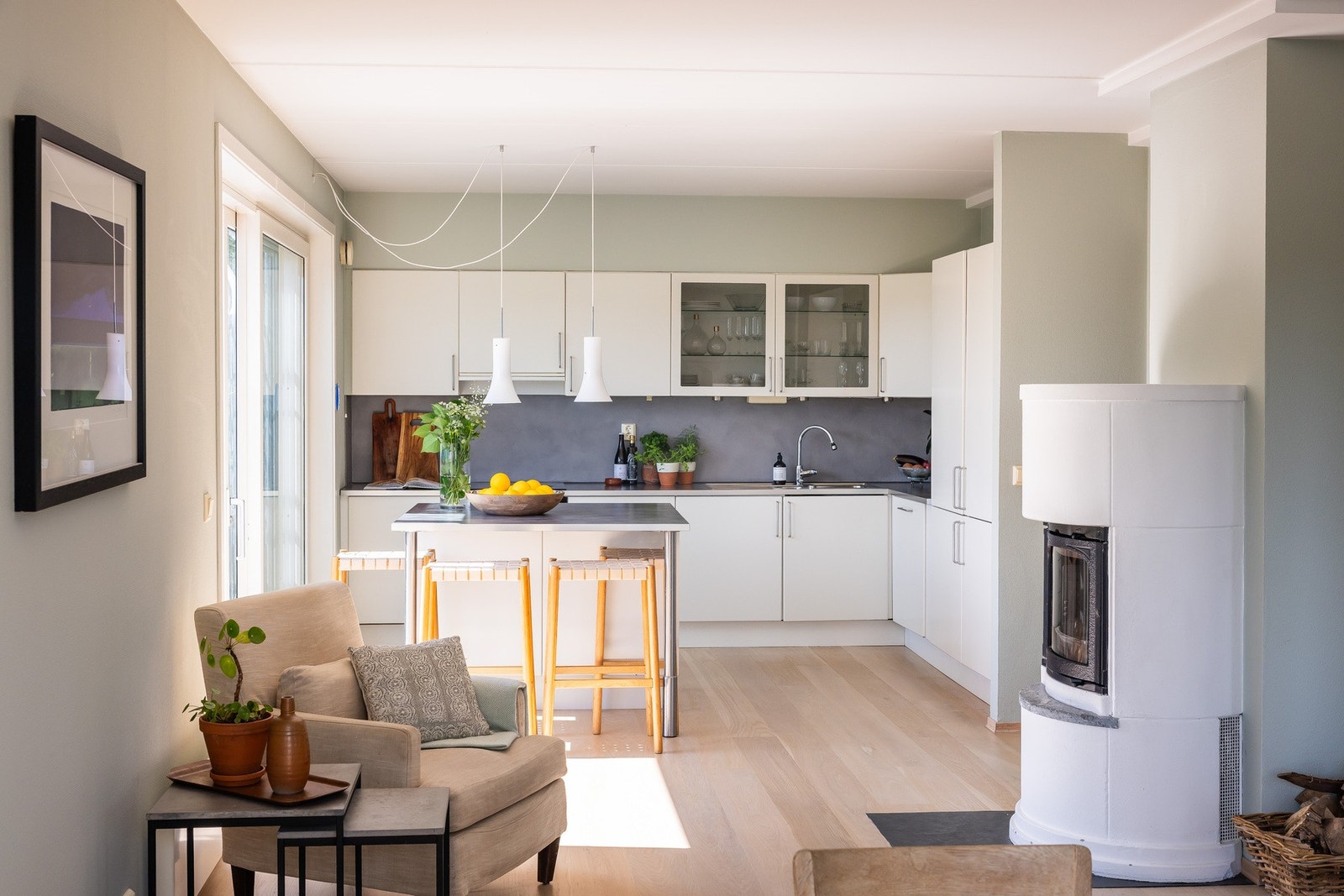 Lekkert kjøkken med kjøkkenøy, integrerte hvitevarer og peisovn som ligger overgangen mellom spisestue og kjøkken. Galleribilde