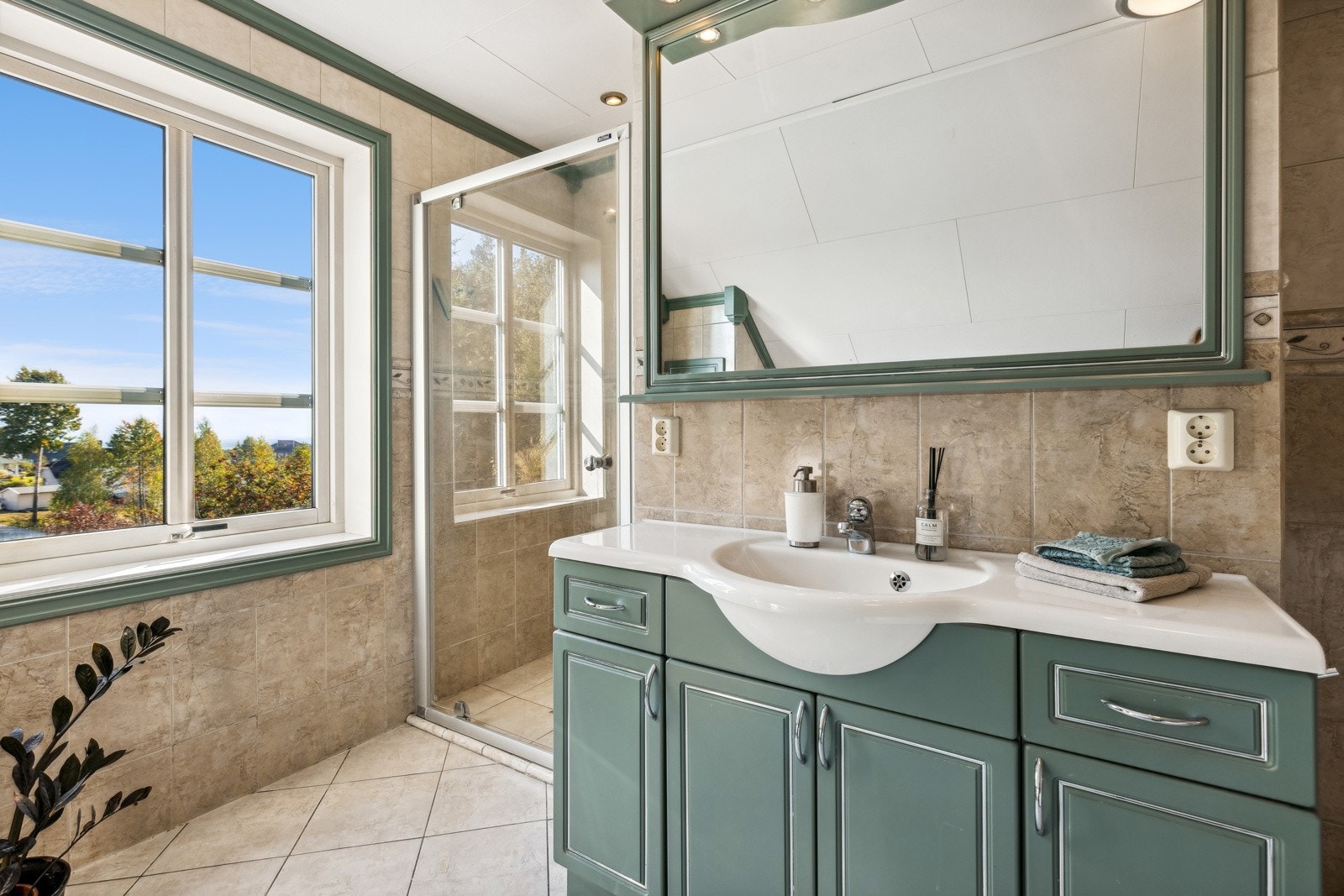 Badet er innredet med dusjnisje, servant, speil, vegghengt klosett og hjørnebadekar. Galleribilde