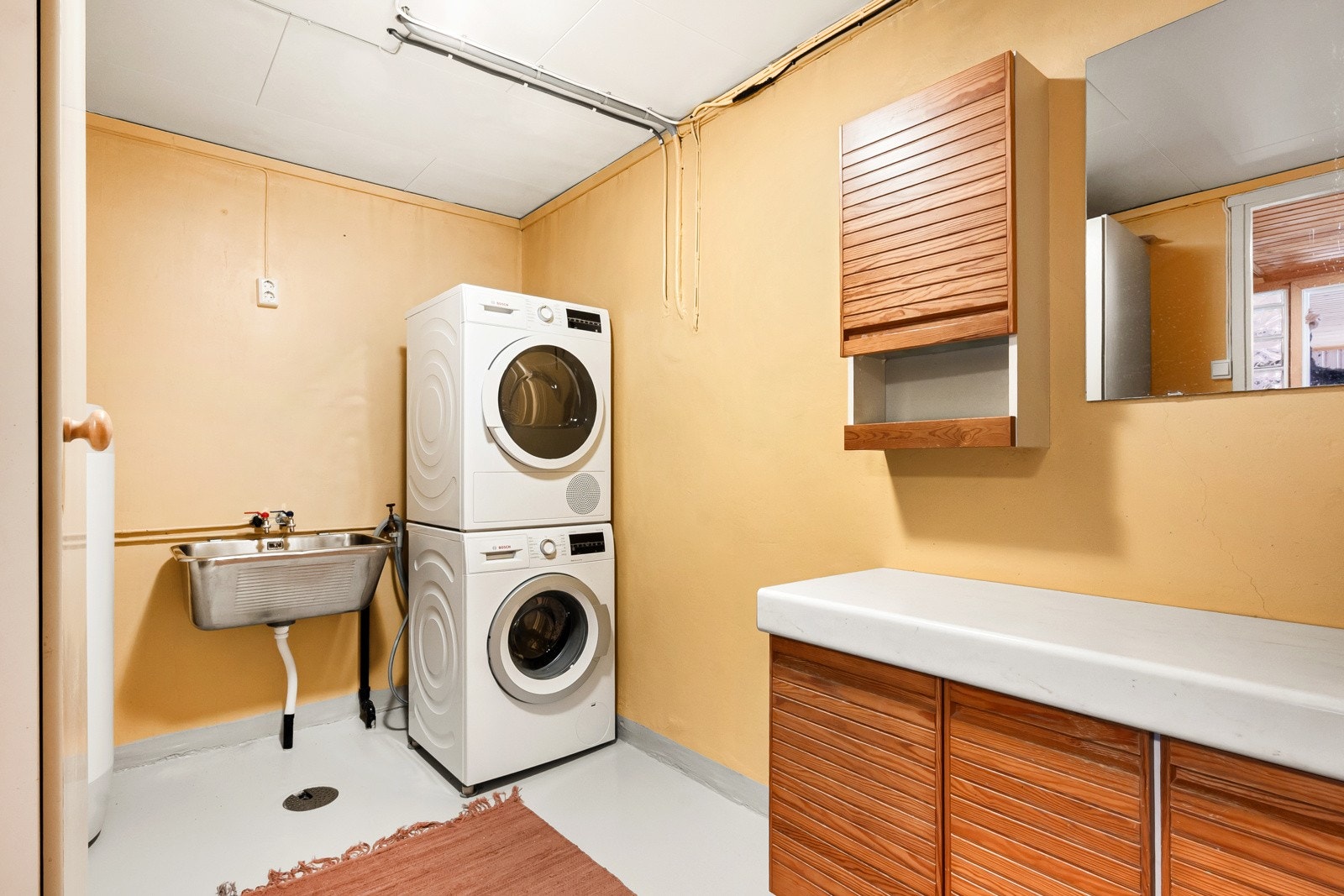 Praktisk vaskerom med opplegg for vaskesøyle og utslagsvask. Galleribilde