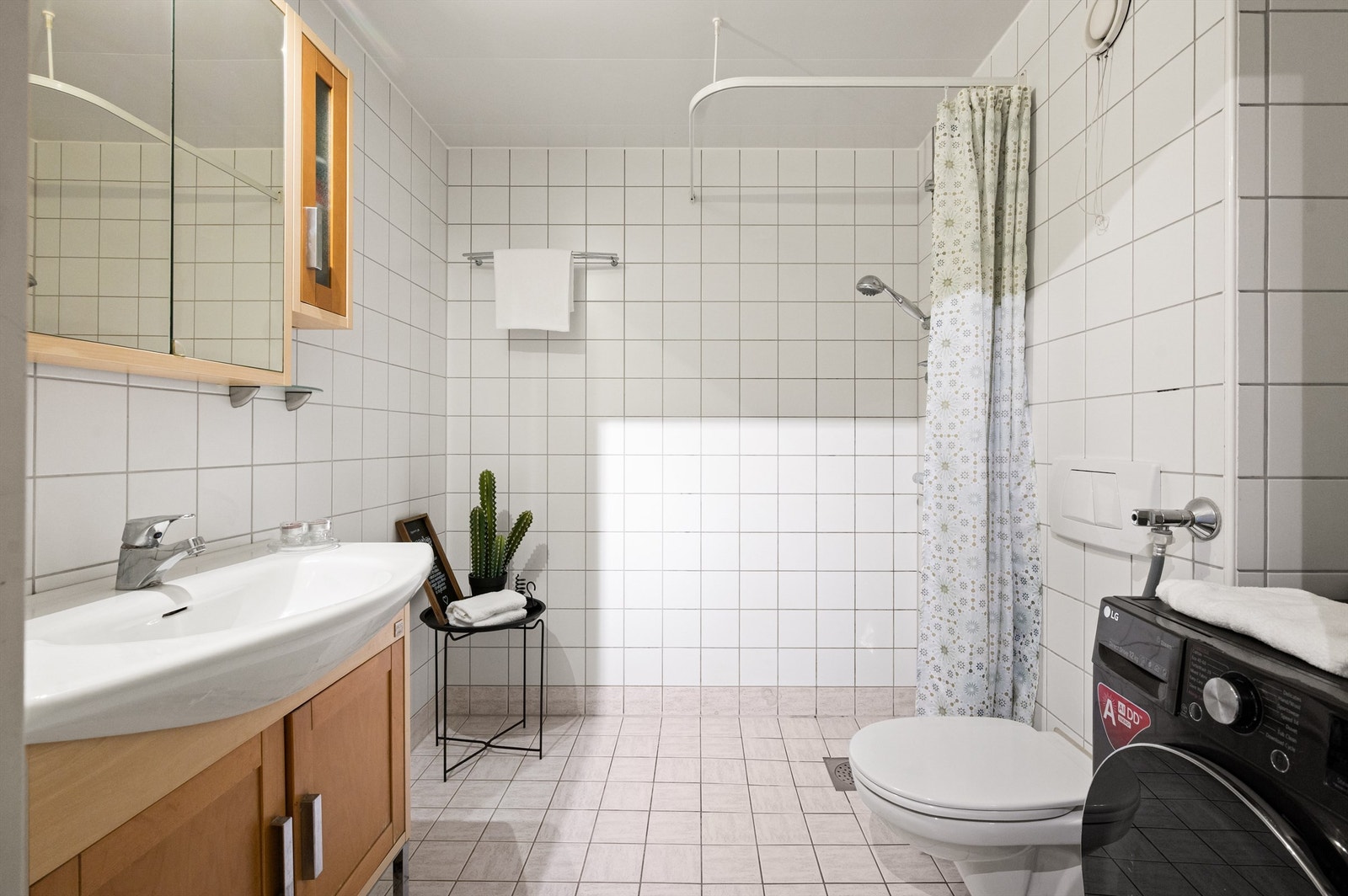 Badet er pent flislagt på gulv og vegger med varme i gulvet. Baderomsinnredningen består av servantskap med servant. Over servanten er det et praktisk speilskap. Galleribilde