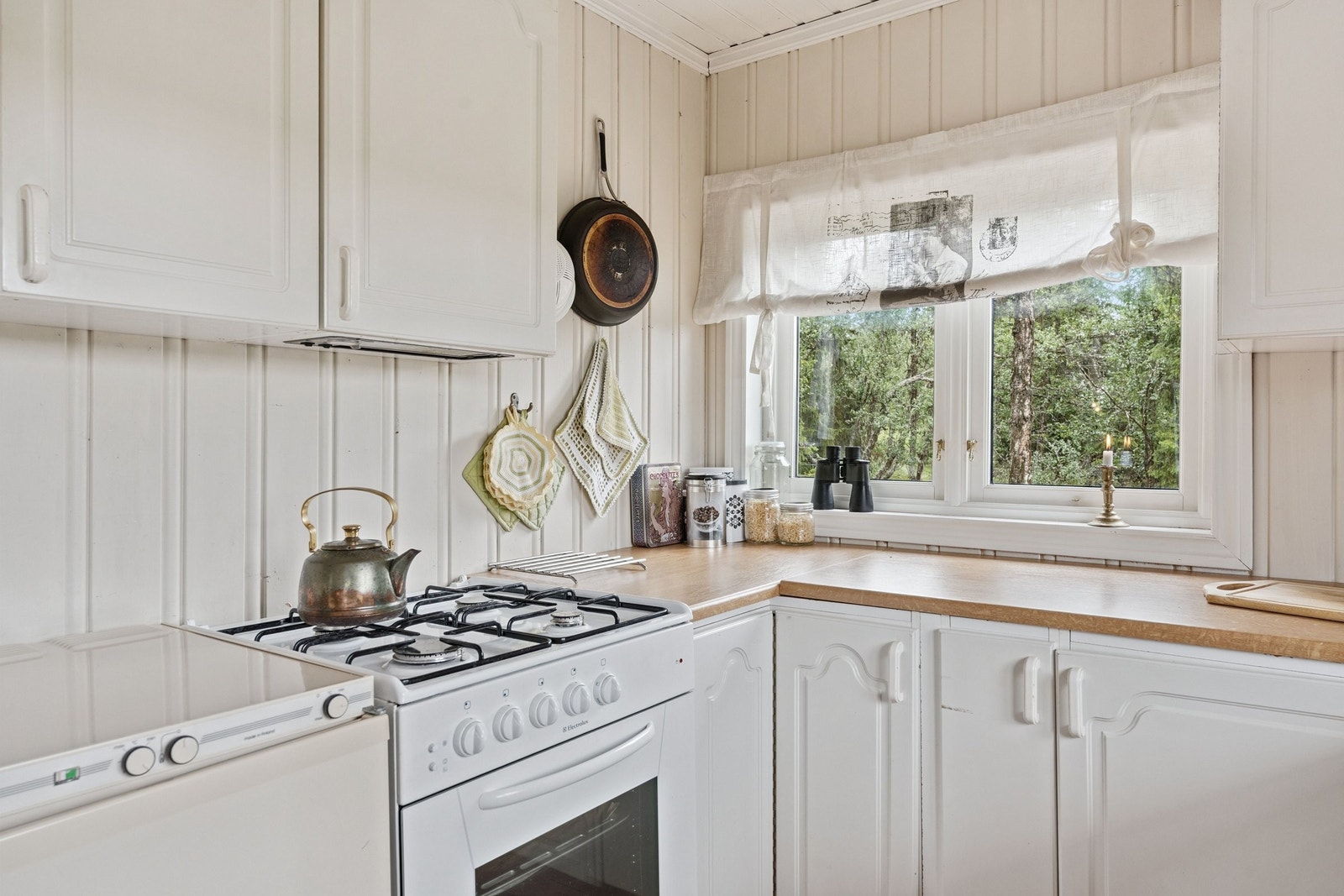 Lyst og innbydende kjøkken med komfyr og kjøleskap som går på gass Galleribilde