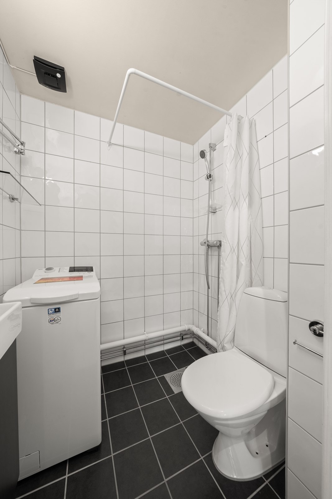 Baderomsinnredningen består av gulvstående toalett, servant med ettgreps blandebatteri, dusjarmatur, plass og opplegg for vaskemaskin. Galleribilde