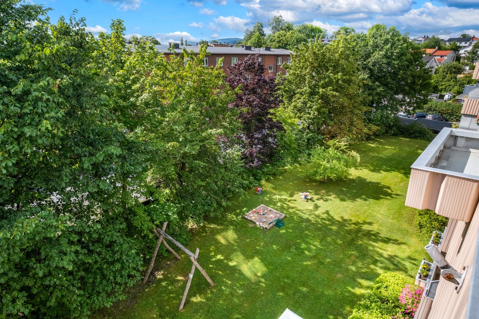 Utsikt over bakgården fra balkongen. Her er det utstyrt med lekestativ, sandkasse og sittegruppe til bruk for beboere. Galleribilde