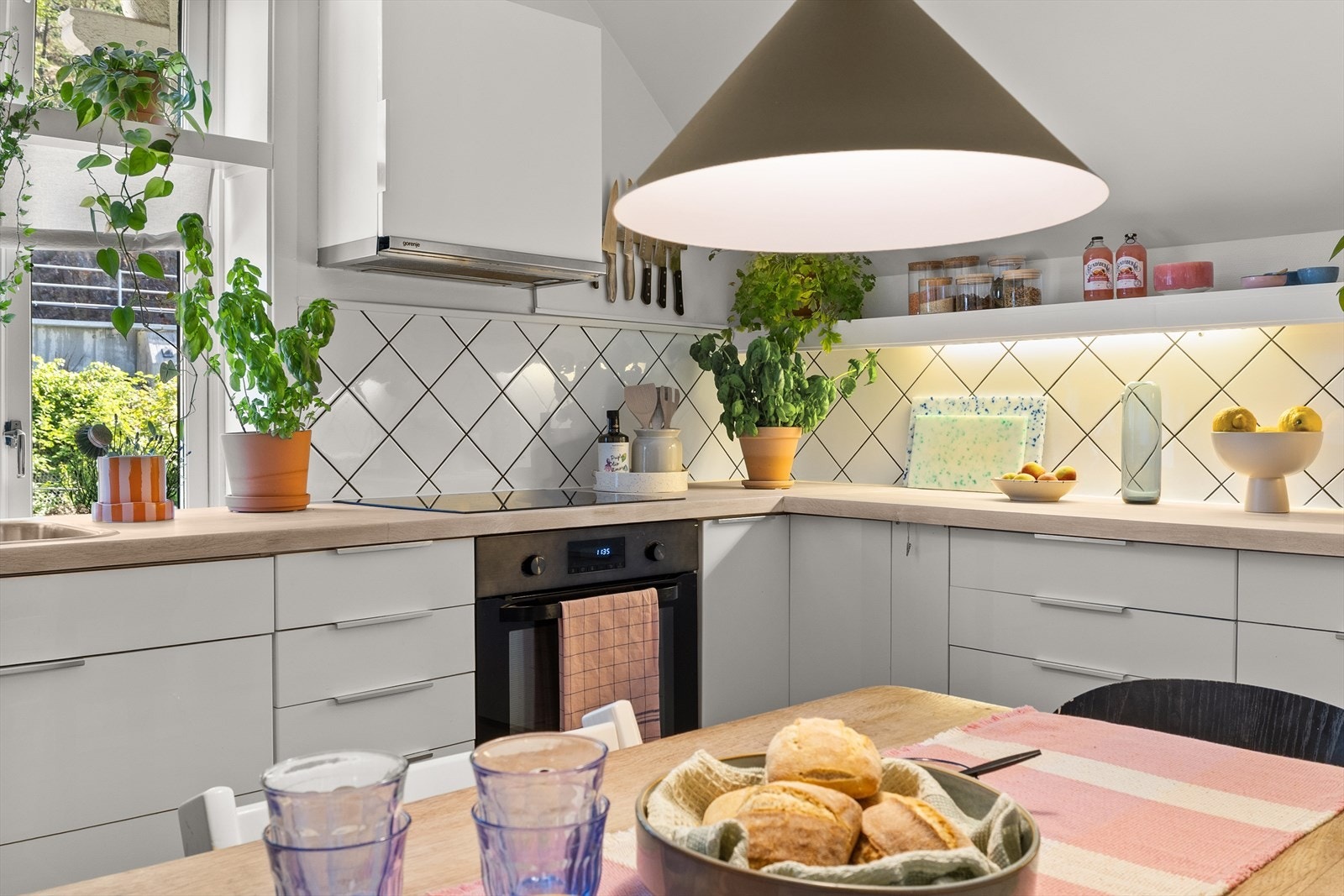 Skråtaket gir en sjarmerende romfølelse, mens åpen hyllereol og flislagt vegg tilfører både karakter og funksjonalitet. Galleribilde