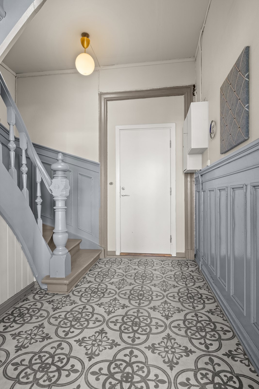 Trappeoppgangen gir et elegant førsteinntrykk med vakre gulv og malte panelvegger i en dempet blågrå tone. Galleribilde