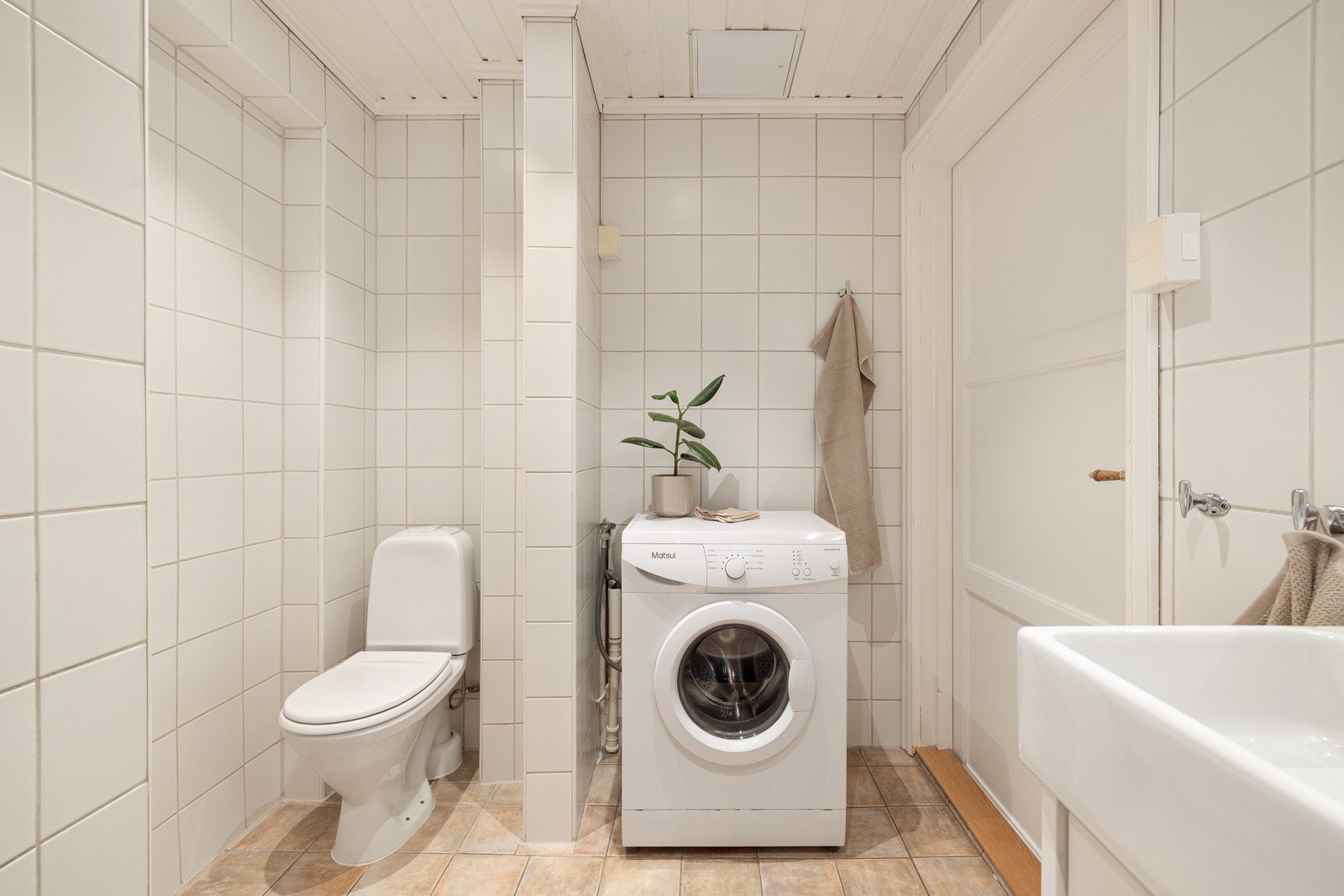 Rommet er innredet med et gulvstående servantskap med ett-greps armatur, vegghengt speil med overbelysning, dusjhjørne, gulvstående toalett og opplegg for vaskemaskin. Galleribilde