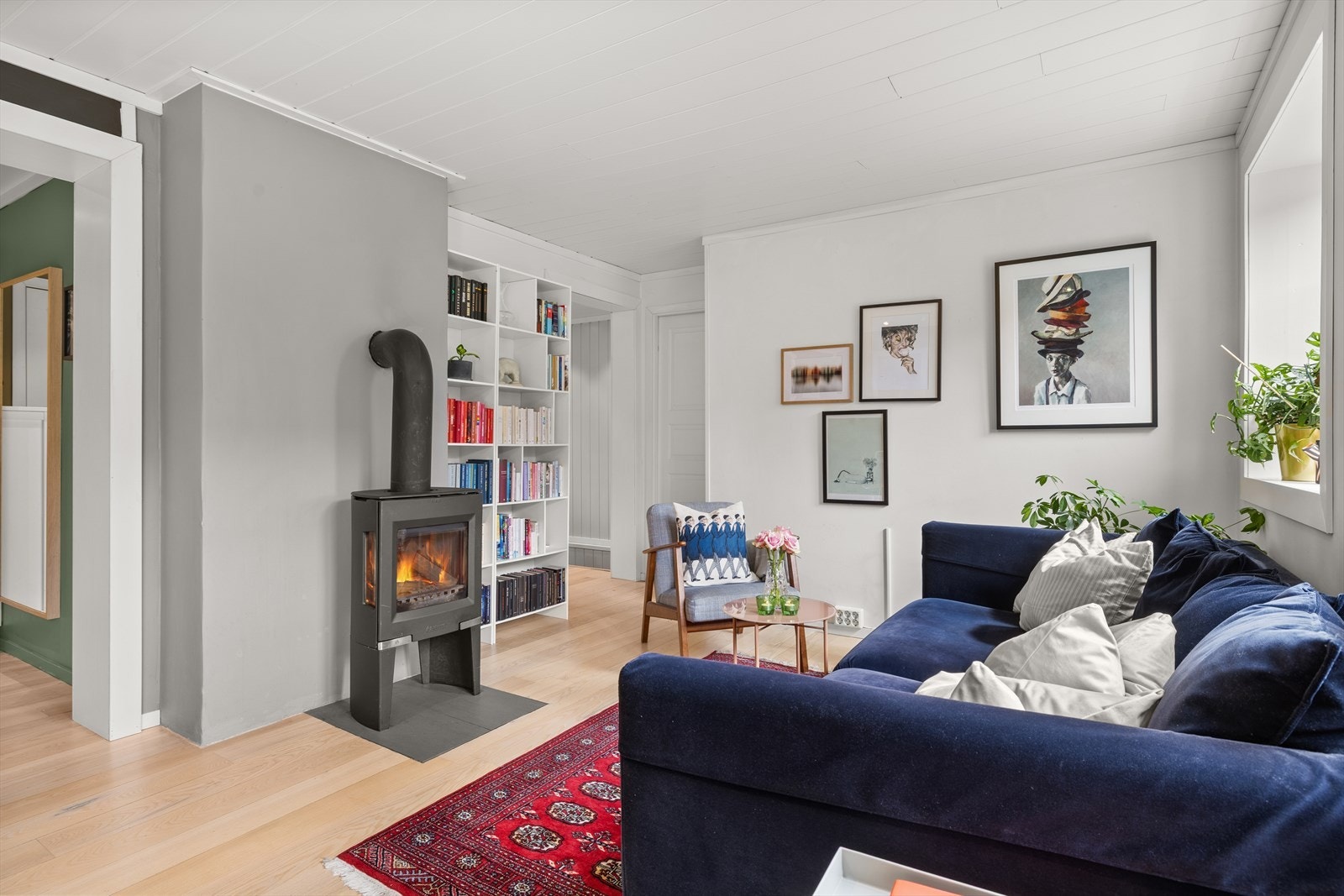 Midt i rommet står en klassisk vedovn som gir både varme og hygge på kjølige dager. Galleribilde