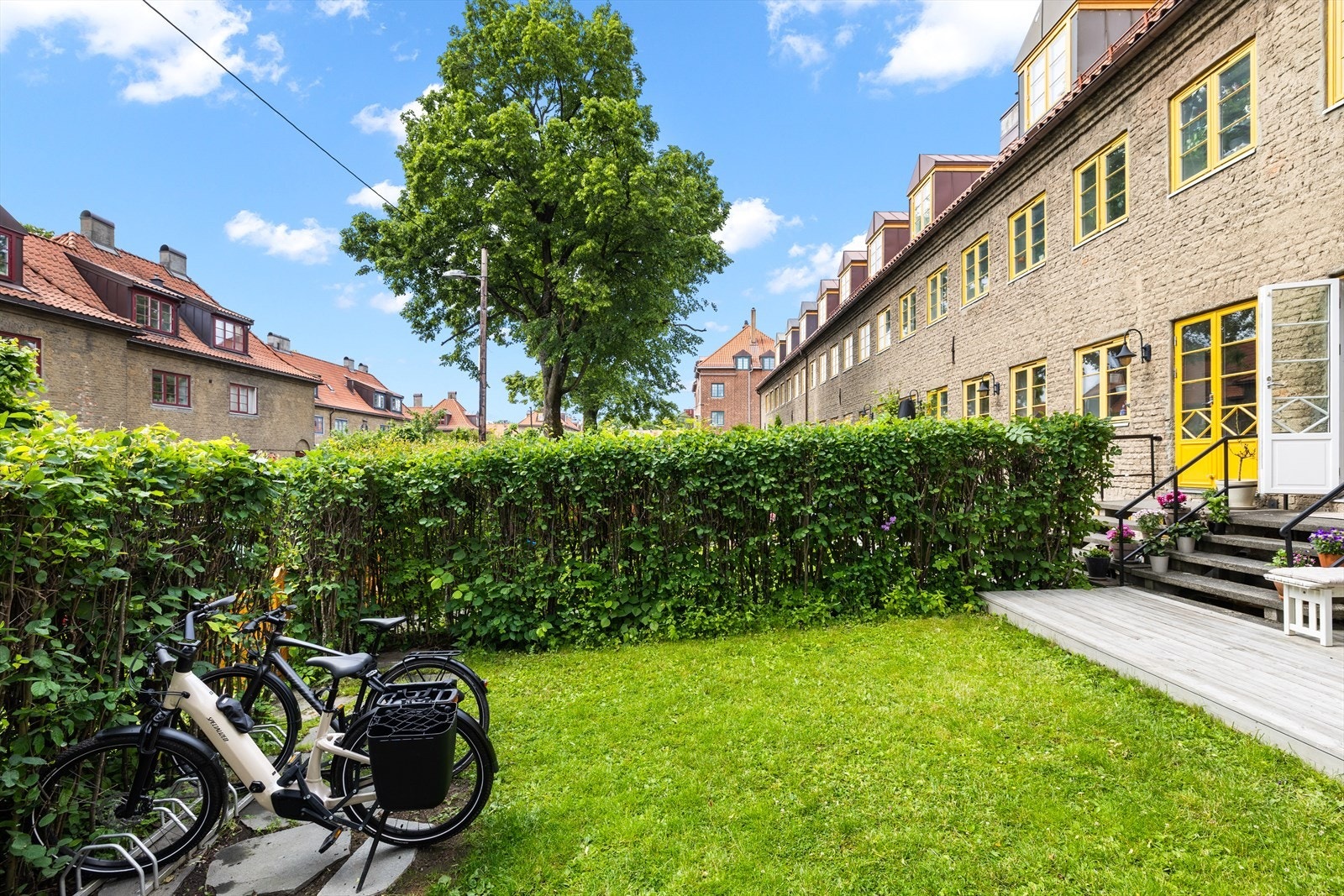 Boligen ligger pent tilbaketrukket i et rolig tun, omgitt av velholdte grøntarealer og fargerike blomstre. Galleribilde