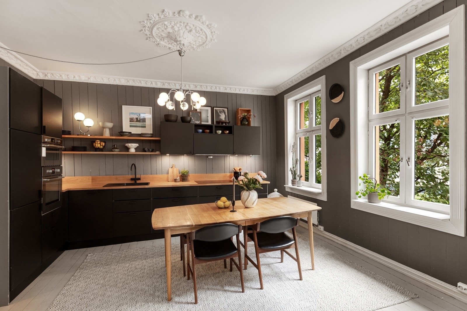 Kjøkkenet ligger i åpen løsning mot stuen og skaper automatisk en romslig og sosial planløsning. Innredningen er fra 2018 og har mørke, slette fronter og benkeplate av heltre. Galleribilde