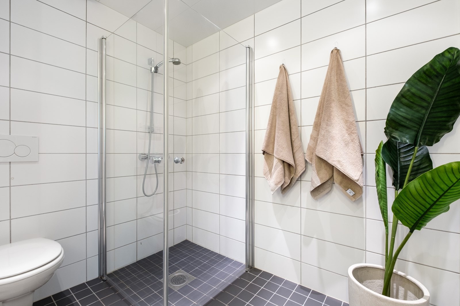 Badet er innredet med vegghengt klosett, servant nedfelt i innredning og dusjhjørne med svingbare glassdører. Galleribilde