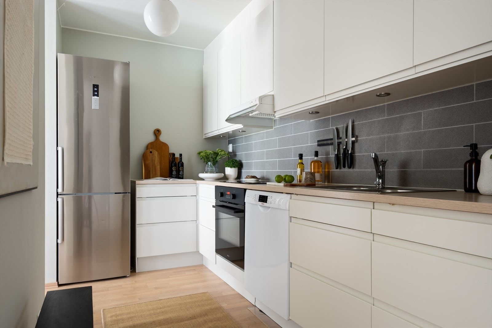 Kjøkkenet har et moderne preg og består av hvite, glatte fronter og benkeplate av laminat med nedfelt vask. Galleribilde