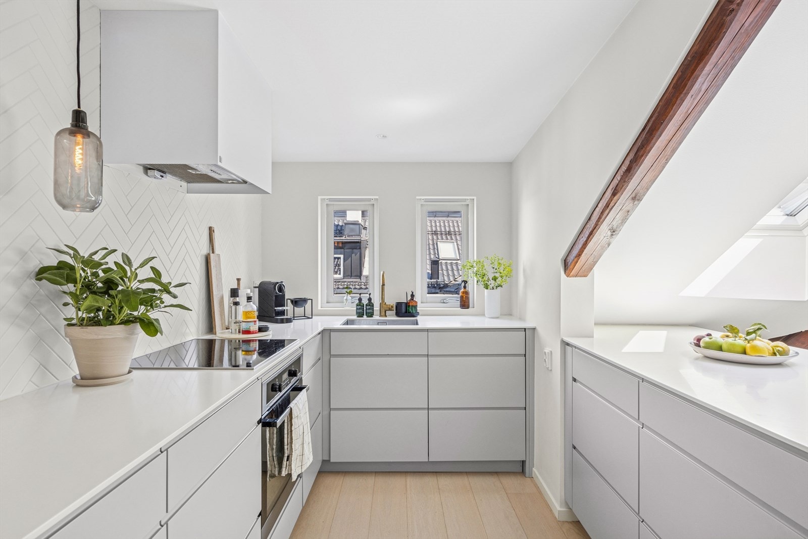 Delikat kjøkkeninnredning med slette fronter og integrerte hvitevarer. Kompositt benkeplate med integrert oppvaskkum og ettgreps blandebatteri. Galleribilde