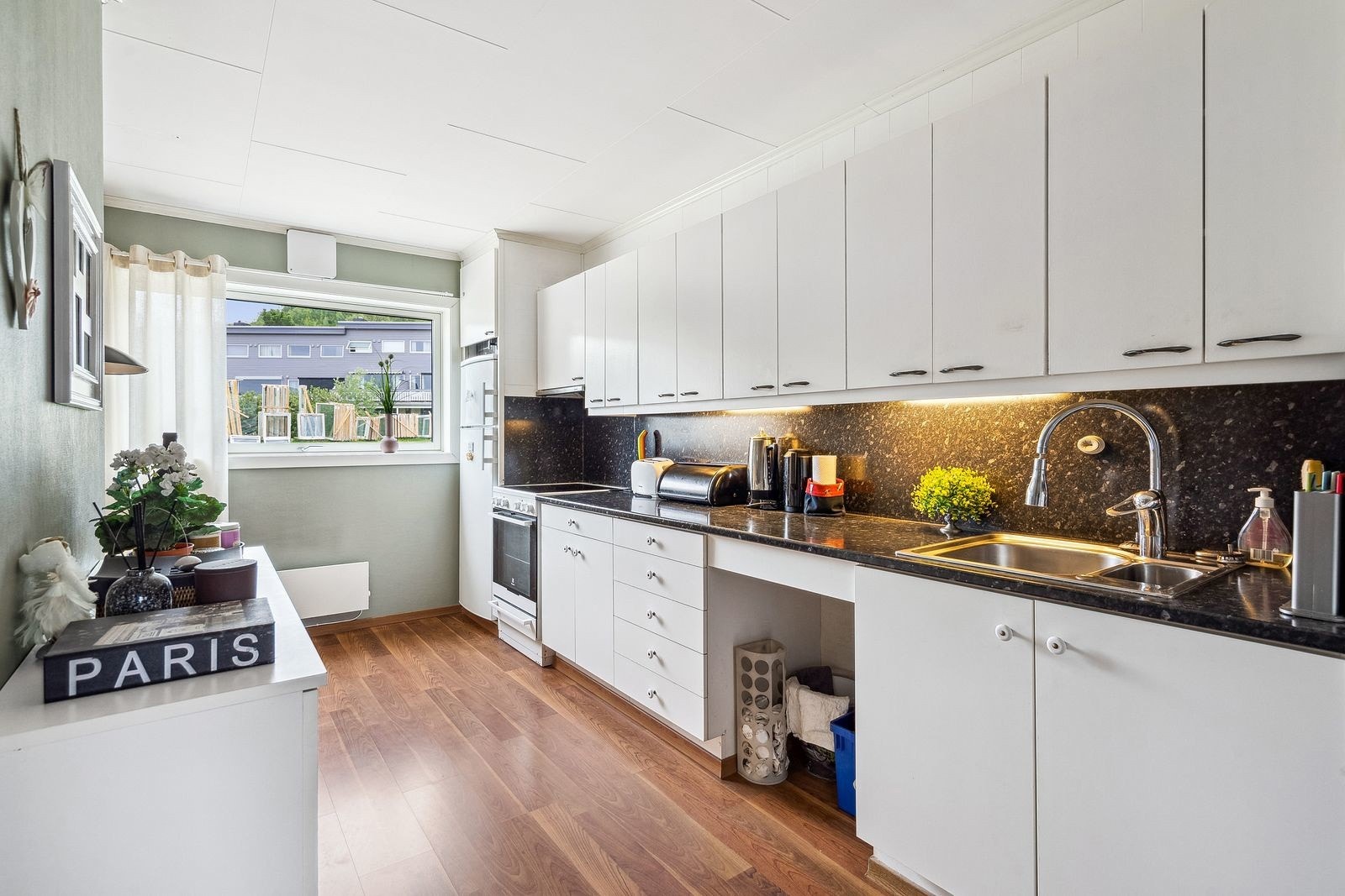 Kjøkken med hvite fronter og godt med skap- og benkeplass. Galleribilde