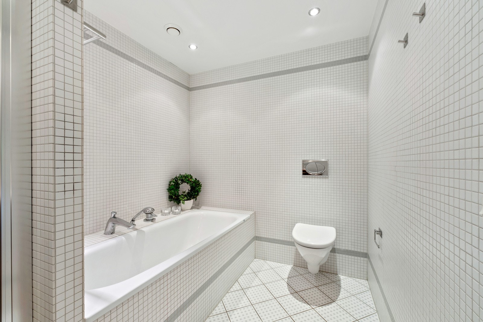 Badet har både dusjnisje og innmurt badekar. Dusjnisjen er avskjermet av skyvbar glassdør og fast glassvegg. Badet har varmekabler i gulv. Galleribilde