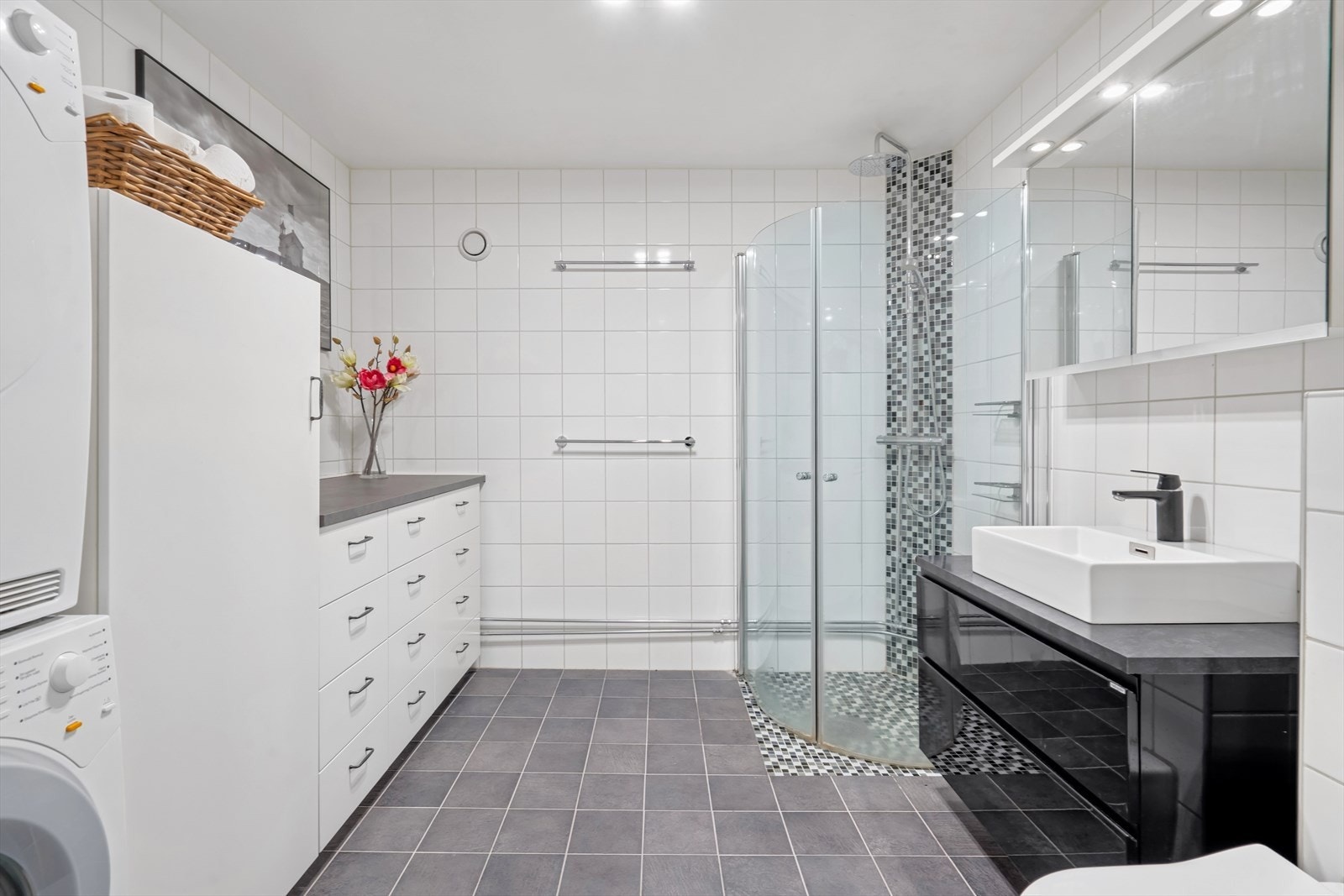 Lekkert og stort flisbelagt bad pusset opp i 2010. Innredningen består av servant med svart underskap og speil med overlys. Galleribilde