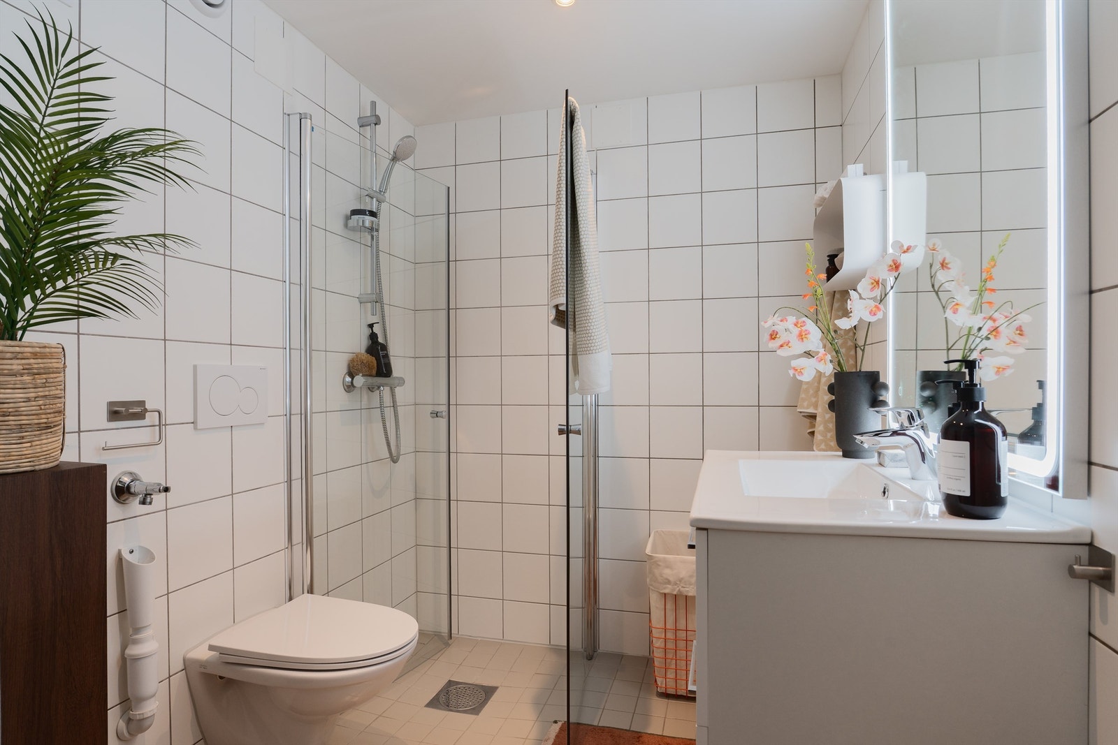 Baderom fra byggeår med ny baderomsinnredning fra 2025. Innfellbare glassdører og vegghengt toalett, samt elektriske varmekabler og spotter i tak. Galleribilde