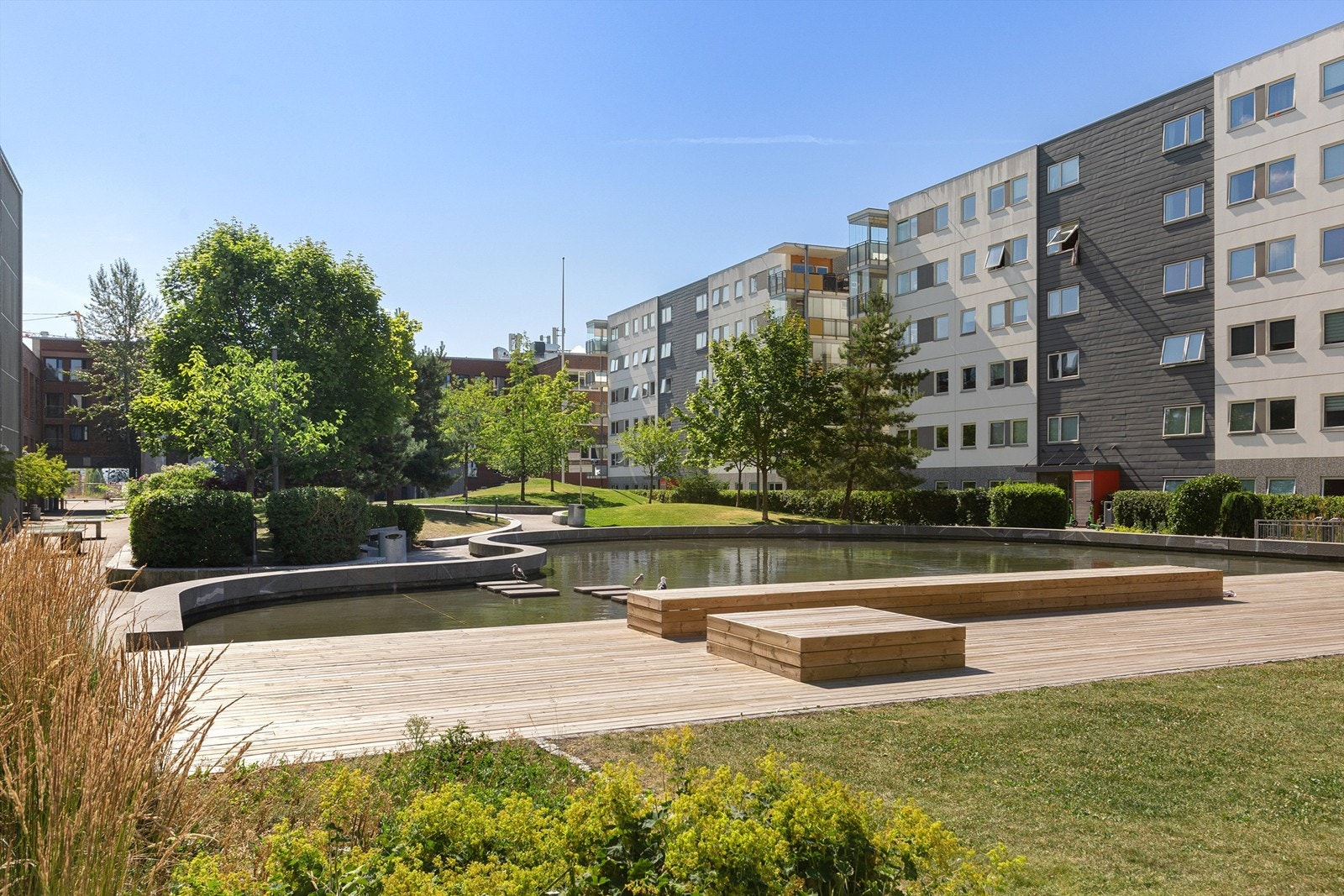 Uteområde med vannspeil, sittegrupper og lekeplass Galleribilde
