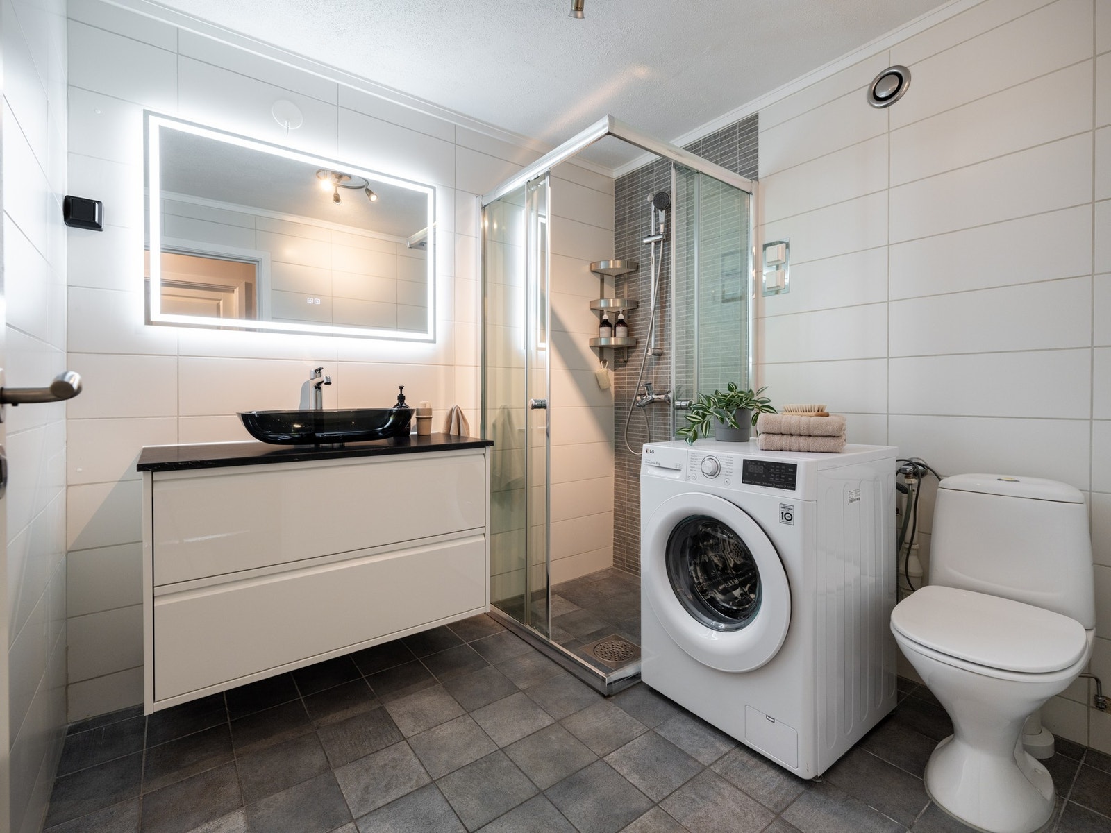 Boligens baderom er bygget opp med lyse fliser på vegger og grå fliser på gulv med varme. Galleribilde