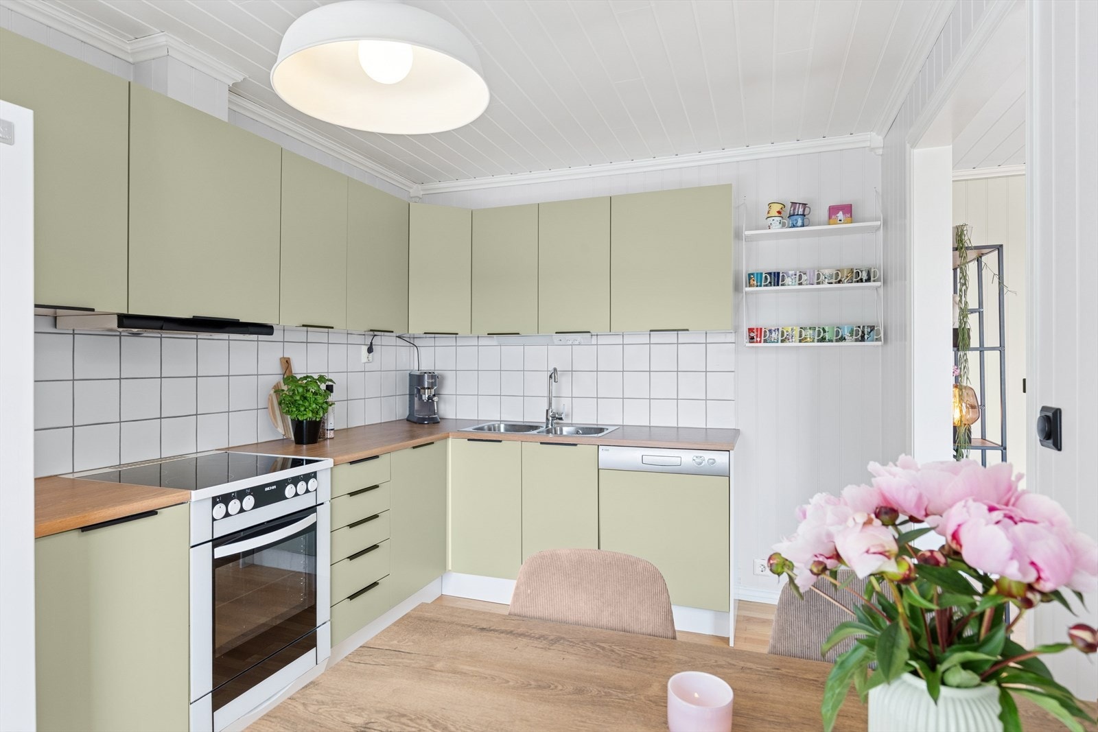 Kjøkkenets innredning er i malt utførelse med laminat benkeplate med nedfelt benkebeslag og to kummer, fliser over benk og kjøkkenventilator med avtrekk ut. Galleribilde