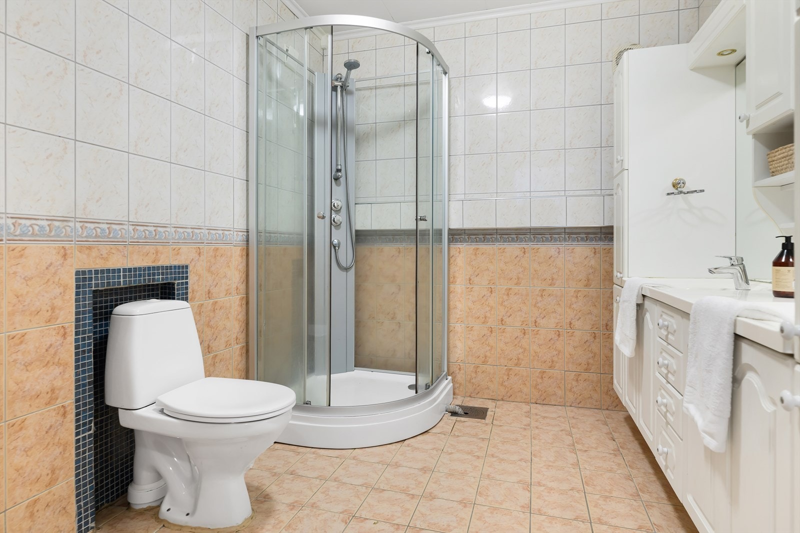 Badet i første etasje er helfliset og innredet med dobbel servant med møbel og speil, dusjkabinett, wc og varmekabler i gulv. Galleribilde