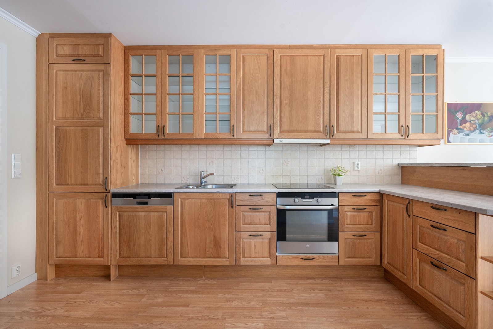 Kjøkkenets innredning har profilerte fronter, benkeplate av laminat, nedsenket oppvaskkum av rustfritt stål, kjøle- og fryseskap, oppvaskmaskin, stekeovn og platetopp. Galleribilde