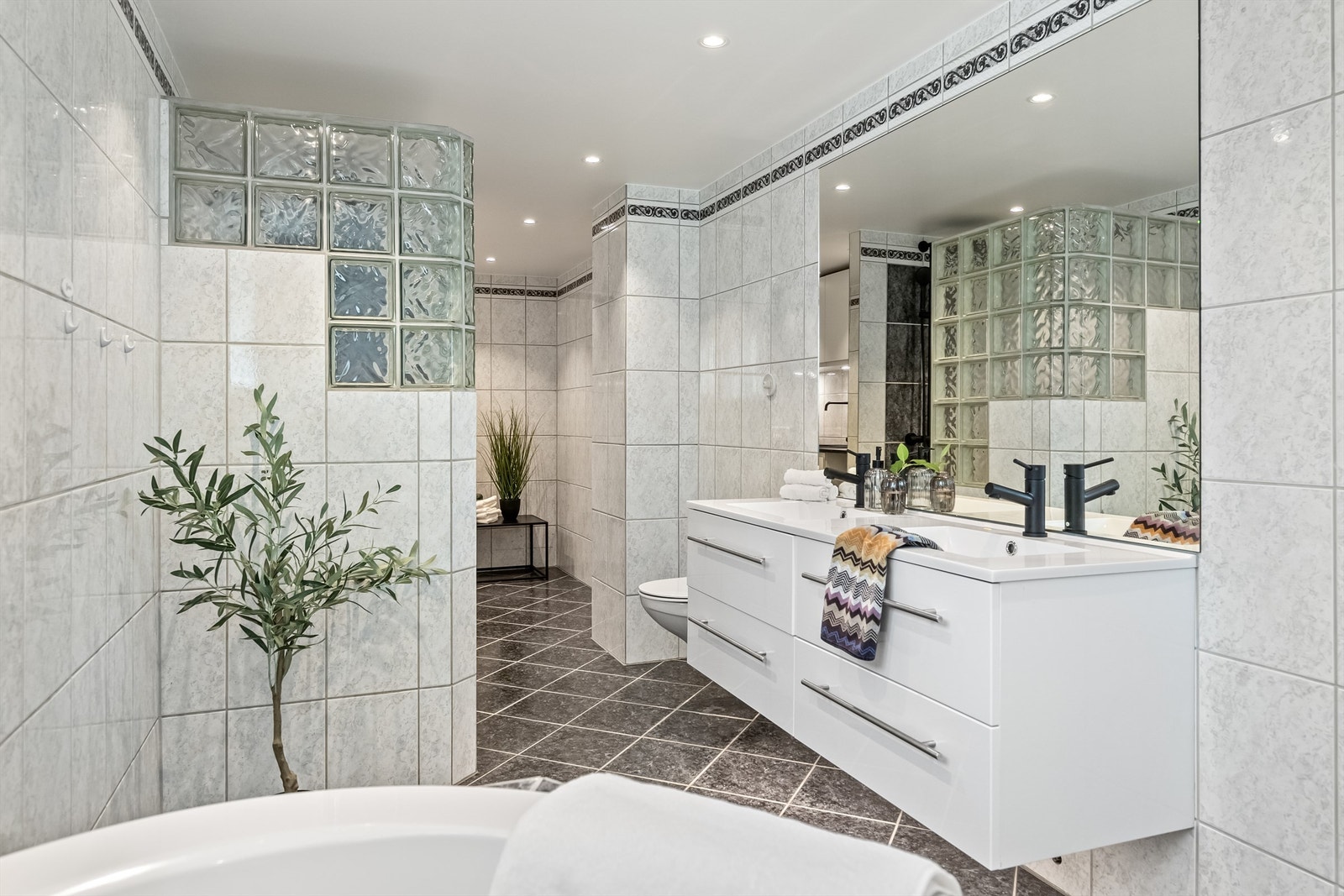 Flislagt bad med varmekabler i gulv og spotter i taket. Galleribilde