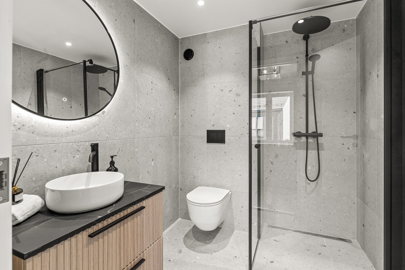 Flislagt baderom som er innredet med overliggende servant, veggmontert toalett, dusjvegger/hjørne. Galleribilde