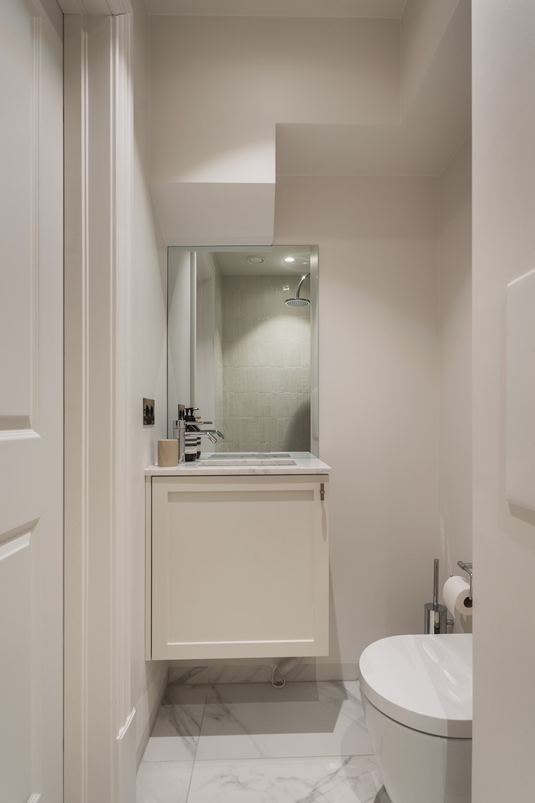 Badet er innredet med lyst servantskap med en elegant servant av marmor og et praktisk vegghengt toalett. Galleribilde