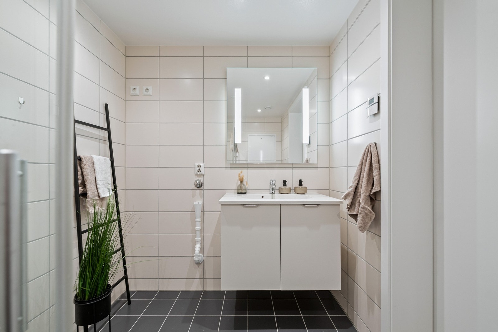 Baderomsinnredning bestående av benkeskap med glatte fronter, og speil med belysning over servant. Galleribilde