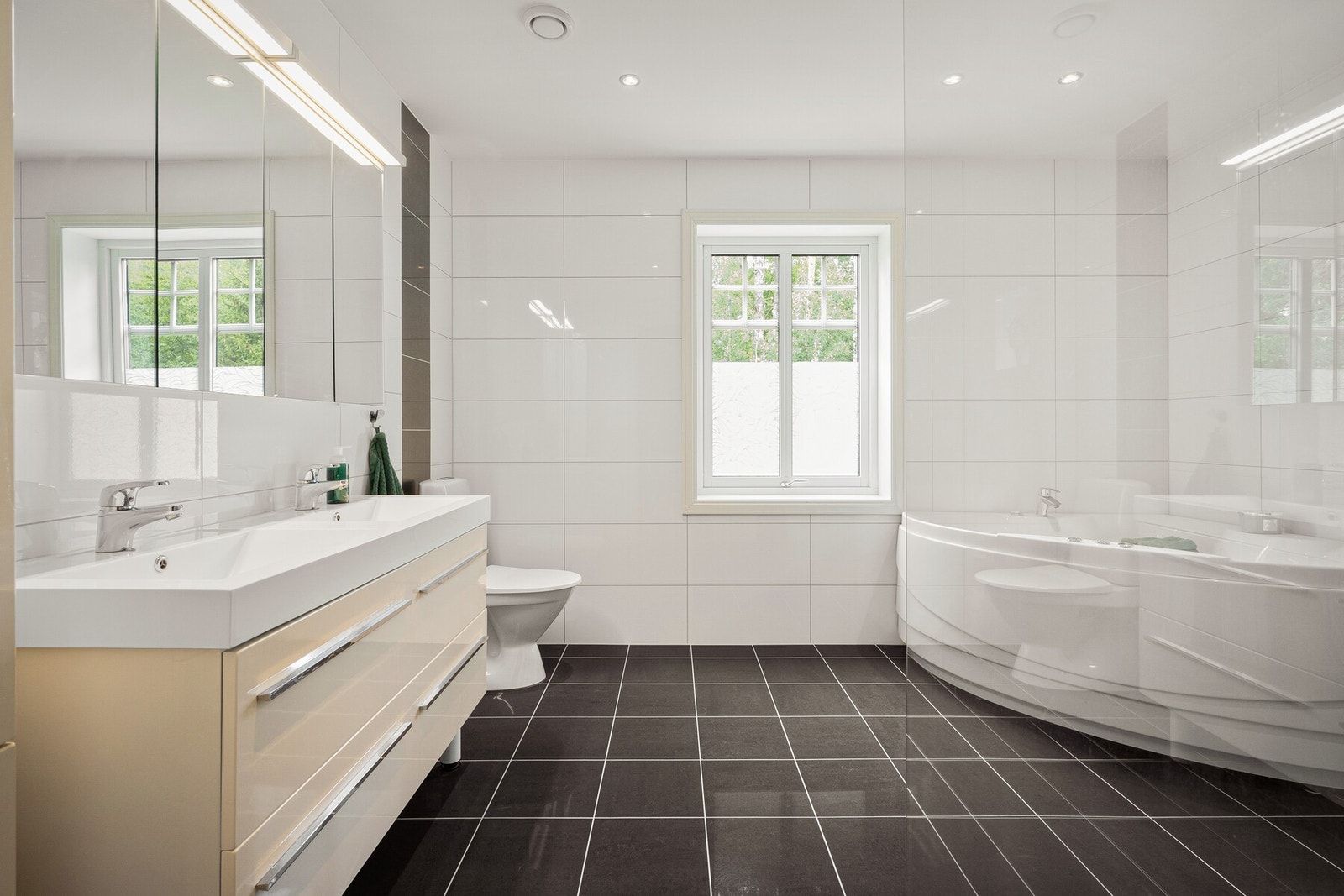 Badet har en romslig dusjløsning, dobbel servant og badekar Galleribilde