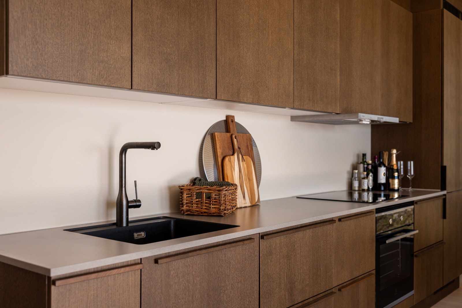 Delikat kjøkkeninnredning fra HTH med integrerte hvitevarer. Focus Mørk Eik Finèr, med høyskap. Lux-skuffer med demping. Vask: Franke Maris Matt Black, med sort blandebatteri inkl uttrekkbar slange. Galleribilde