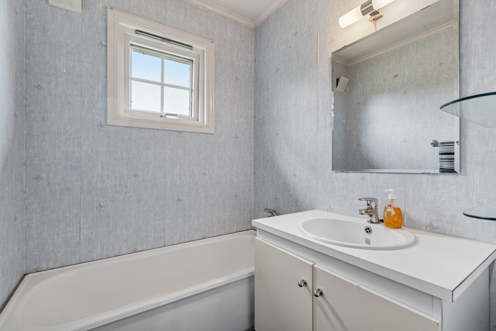 Badet er utstyrt med badekar, baderomsinnredning med servant og speil, samt hyller for oppbevaring. Galleribilde