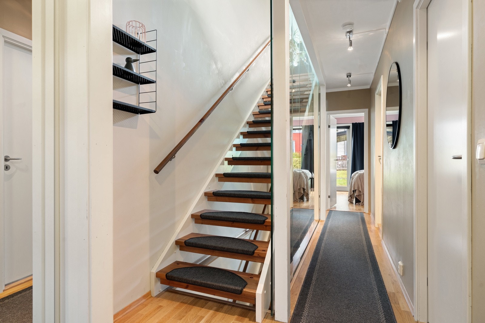Fra entréen ankommer man et gangareal som fordeler seg til to soverom, baderom, samt trappeløp til øvrige etasjer. Trappen er utført med stilfull glassvegg som gir et moderne uttrykk som er gjennomgående i alle etasjer. Galleribilde