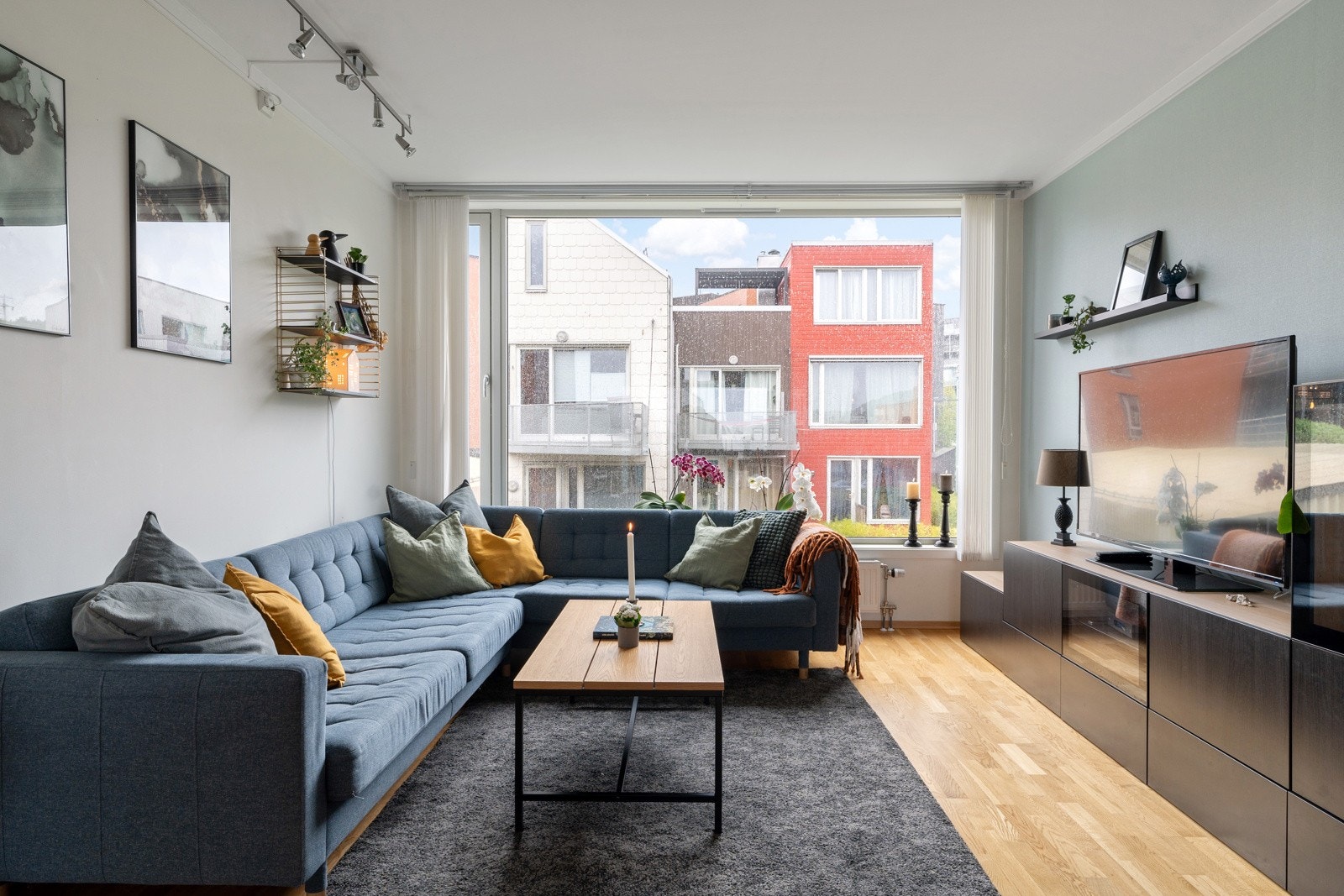 Stuen har parkett på gulv, moderne farger på vegg og flotte panoramavinduer som gir godt innlys Galleribilde