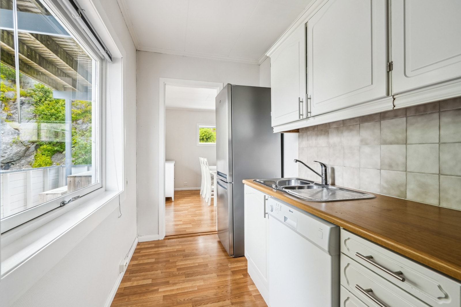 Flott kjøkken med frittstående komfyr, oppvaskmaskin og kjøleskap med fryser. Galleribilde