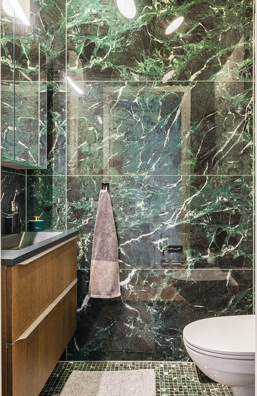 I tillegg har leiligheten et praktisk toalettrom. Dette er flislagt i stilige fargekombinasjoner og har gulvvarme, vegghengt servantinnredning med ovenpåliggende servant, speilskap med overlys og vegghengt toalett. Galleribilde