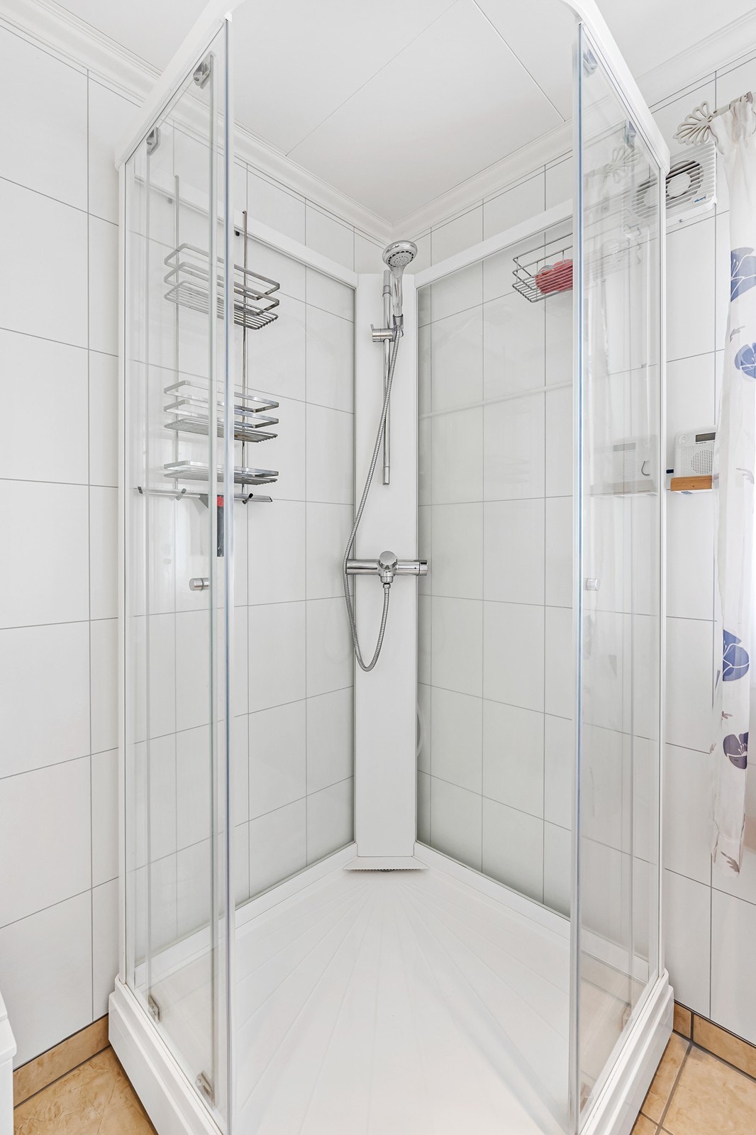 Badet er innredet med gulvstående toalett, dusjkabinett og enkel vask med skapinnredning og speil. Galleribilde