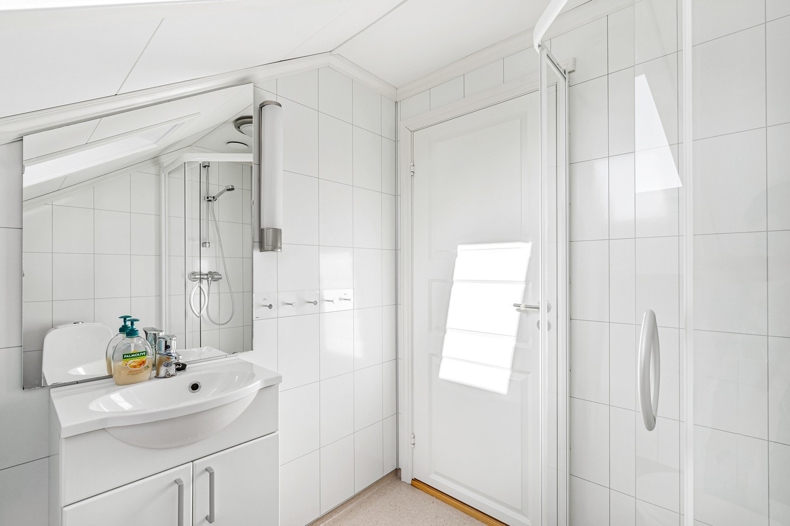 Badet på loftet har gulvbelegg, baderomsplater på vegger og plater i himlingen. Her er det innredet med gulvstående toalett, dusjrom og enkel vask med skapinnredning og speil. Galleribilde