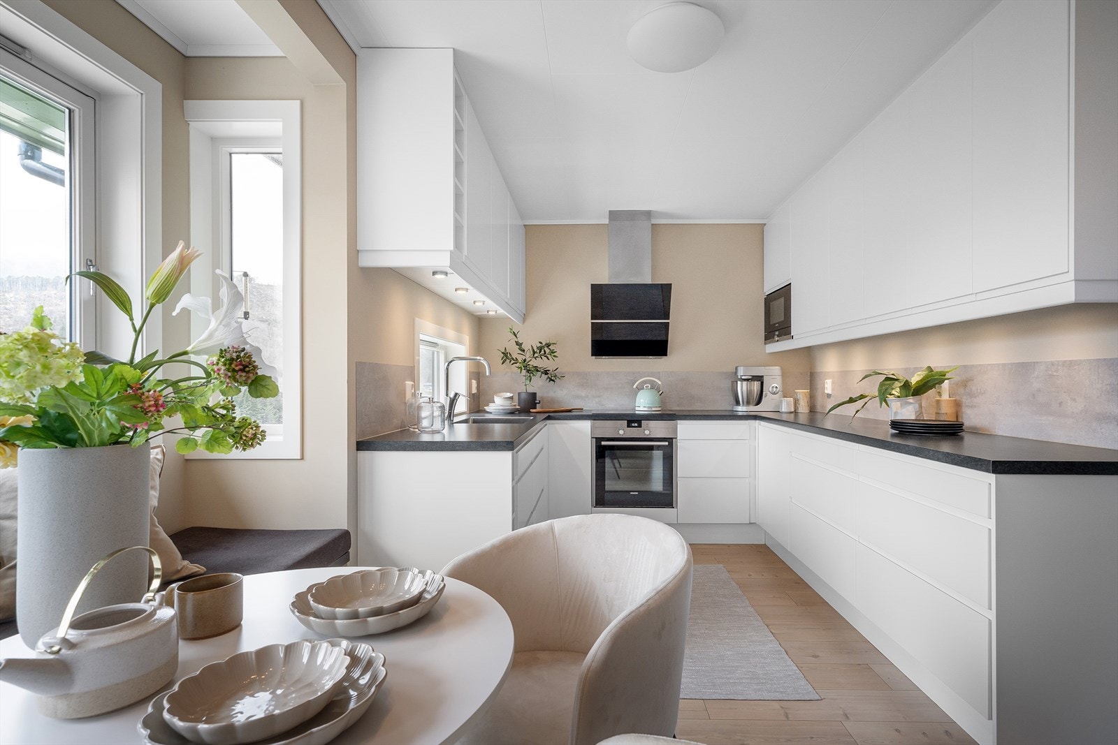 Lekkert kjøkken med en trivelig spiseplass og takhøy kjøkkeninnredning Galleribilde