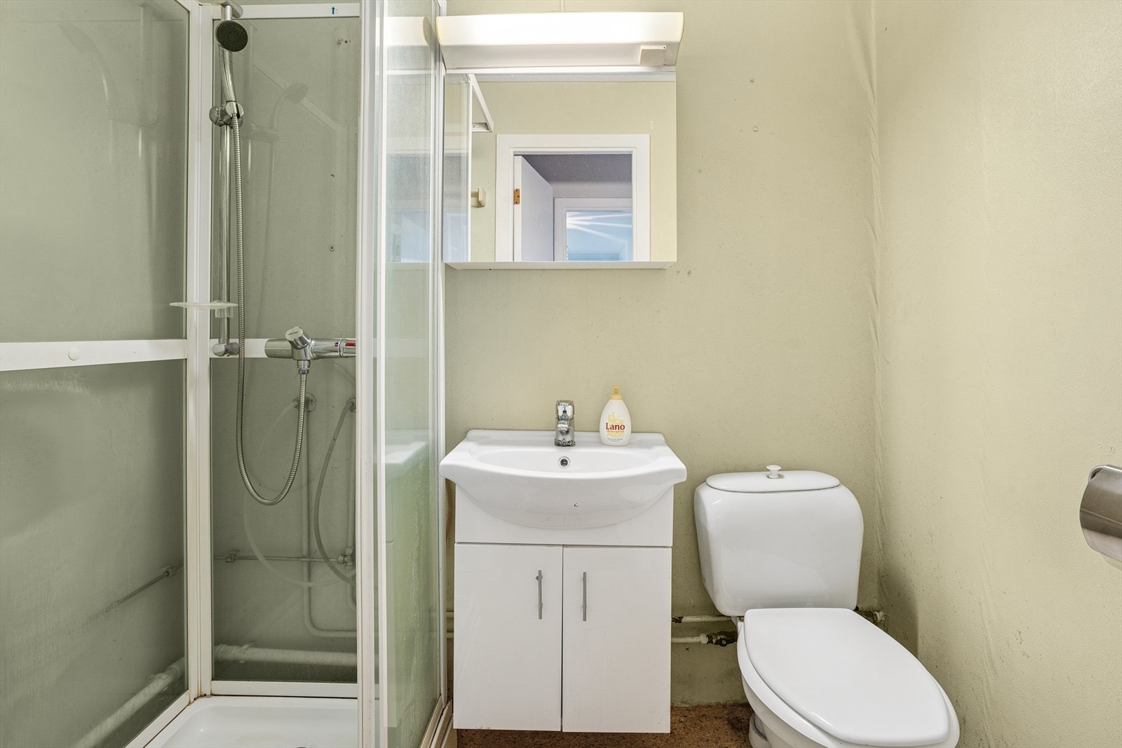 Badet har overflater med belegg på gulv, tapet på vegger og malt betonghimling. Galleribilde