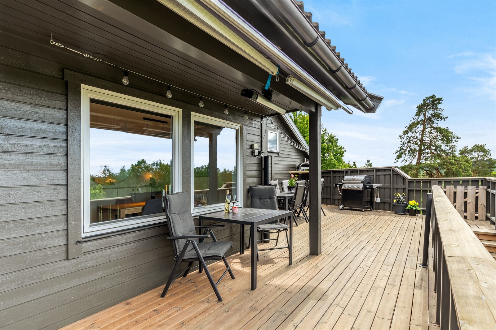 Terrasse med elektrisk markise for solskjerming og varmelampe, vinduene i stuen har også påmontert sol/UV-film Galleribilde