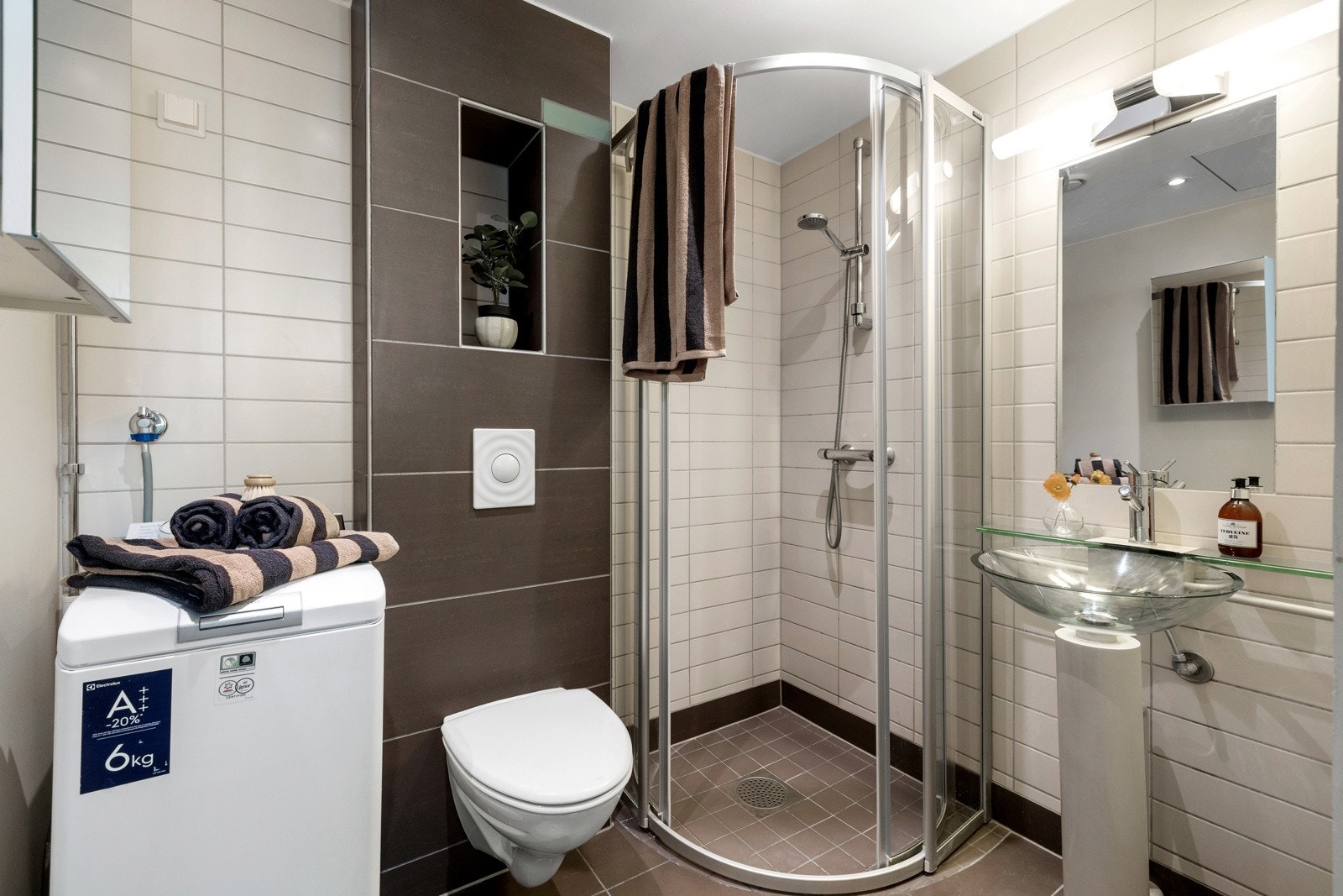Badet er flislagt og innredet med dusjhjørne, enkel servant og vegghengt toalett. Det er opplegg for vaskemaskin Galleribilde