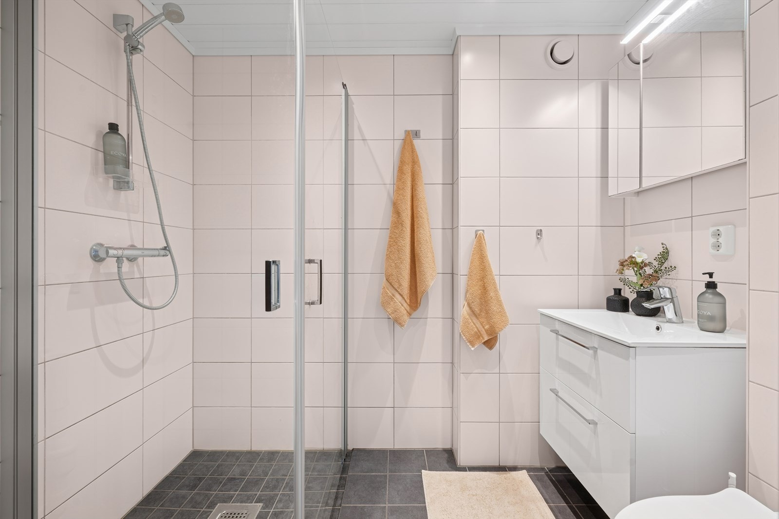 Delikat og tidløst helfliset bad (oppusset i 2019 i regi av borettslaget). Rommet har dusjhjørne, klosett og servant i innredning samt opplegg for vaskemaskin. Et godt sted å starte dagen! Galleribilde