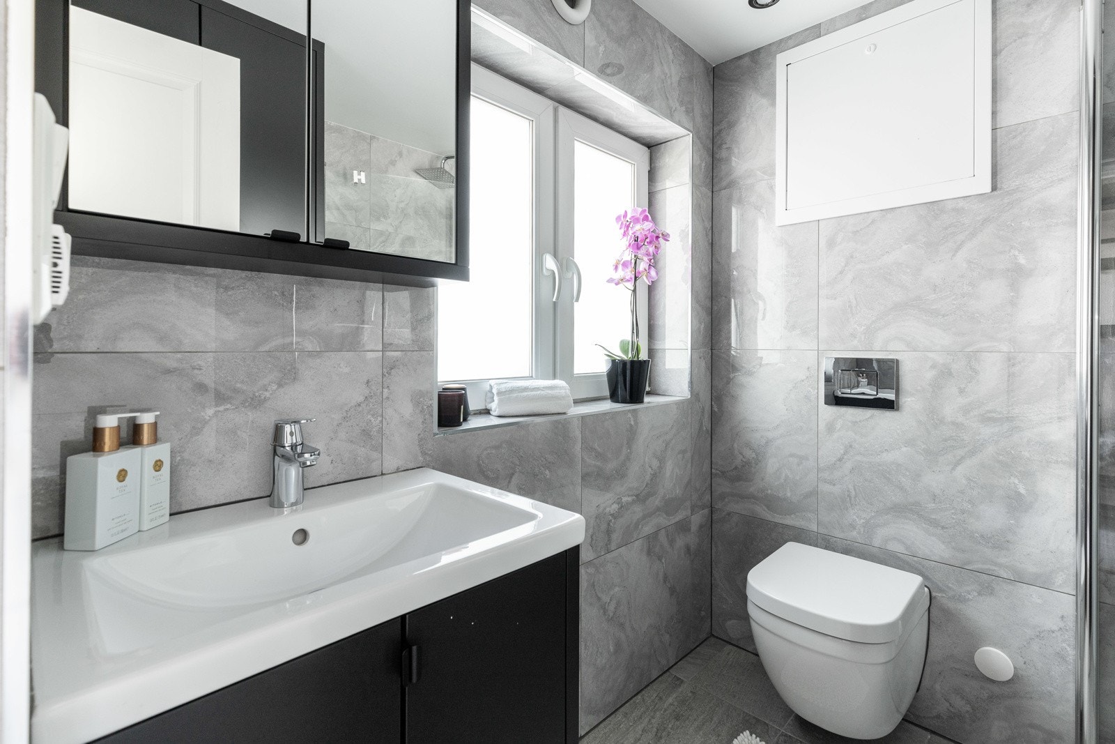 Badet ble pusset opp i 2020, innredet med store, grå fliser for et stilrent uttrykk. Galleribilde
