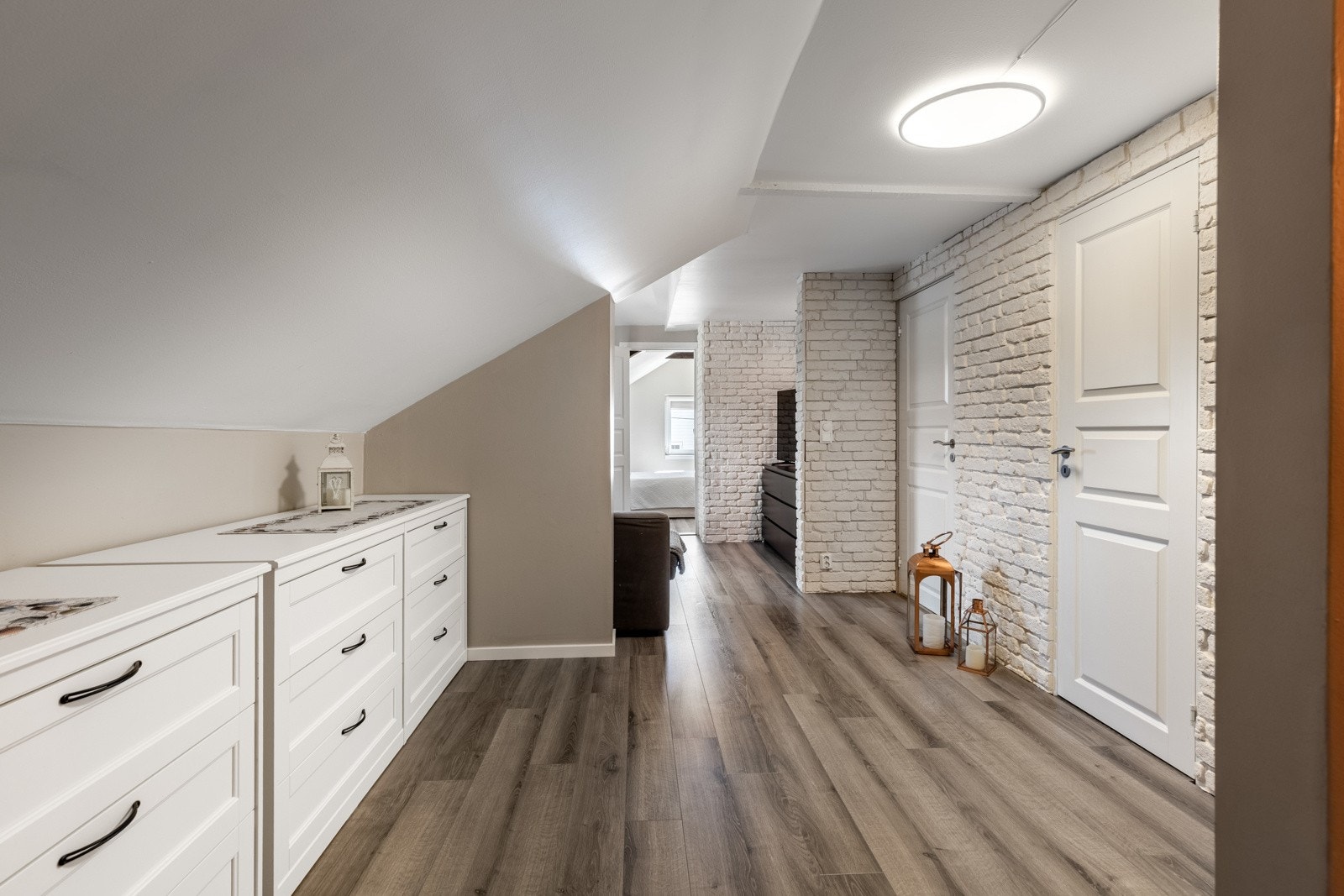 Stuen ligger i andre etasje, med downlights og en varmepumpe fra 2020. Gulvet har 1-stavs lamiant, mens veggene er kledd med hvitmalt teglstein og kaffebrun/beige malte flater. Galleribilde