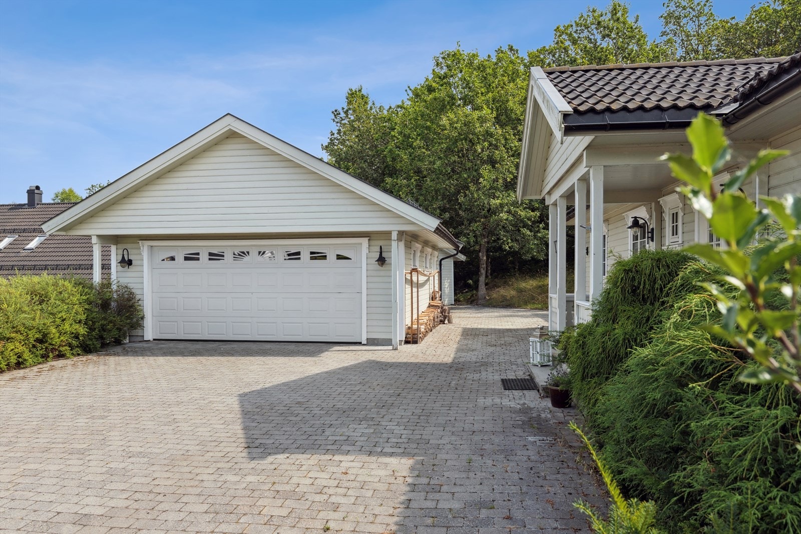 Parkering i dobbelgarasje og steinbelagt gårdsplass med flere parkeringsmuligheter. Galleribilde