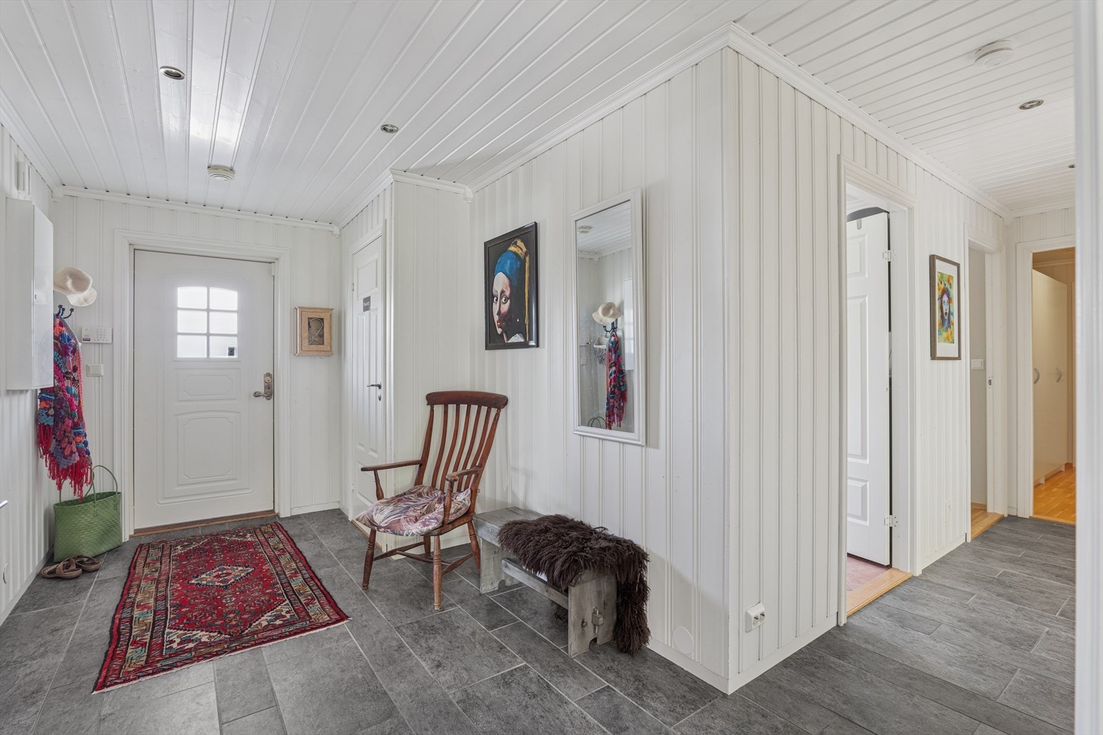 Her møter man hvite trepaneler på vegger og tak, kombinert med grå steinfliser på gulvet - en praktisk og elegant løsning som tåler daglig bruk. Galleribilde